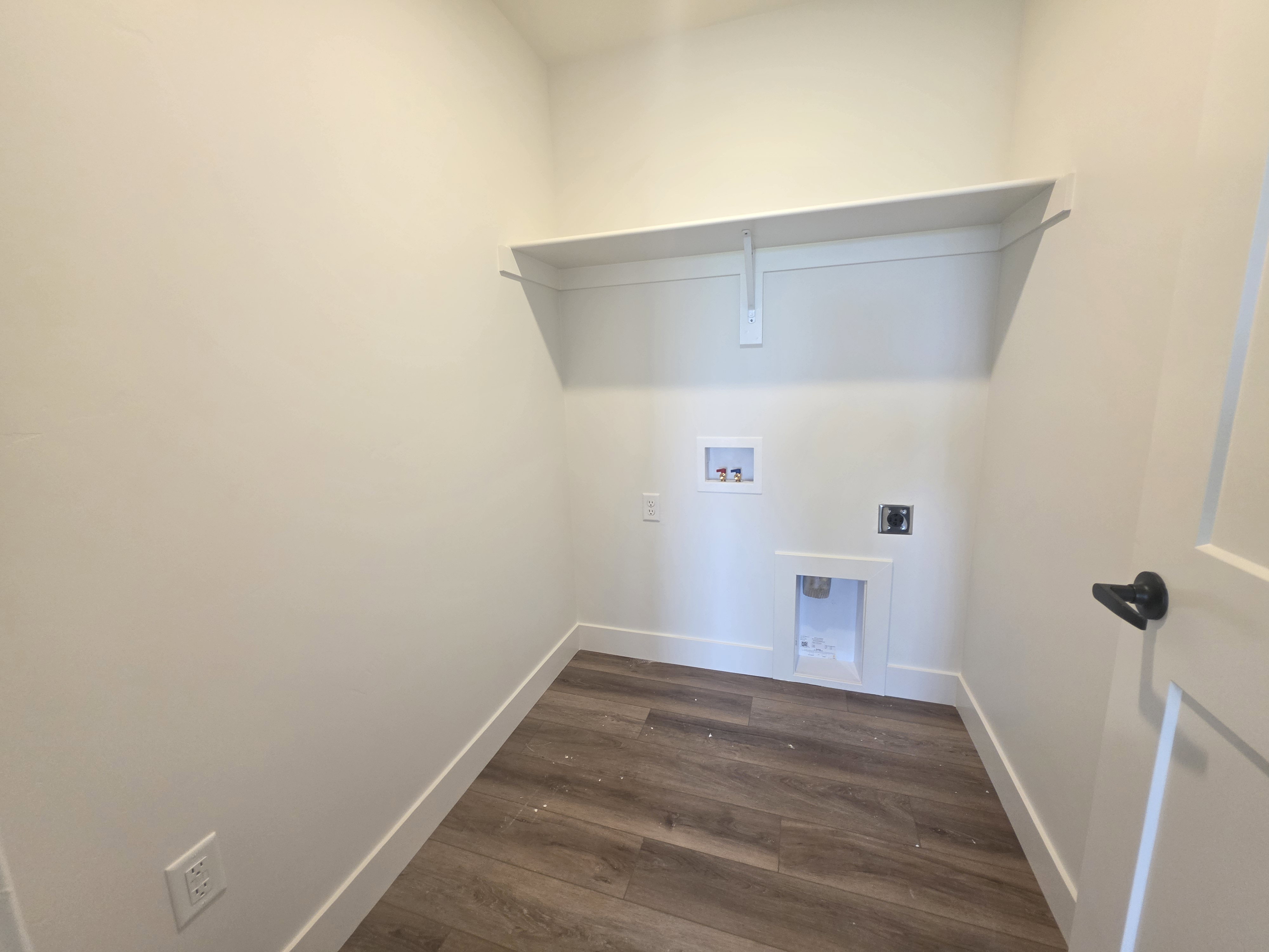 Utility room with wood-finish flooring, white baseboards, a built-in shelf, and appliance connections