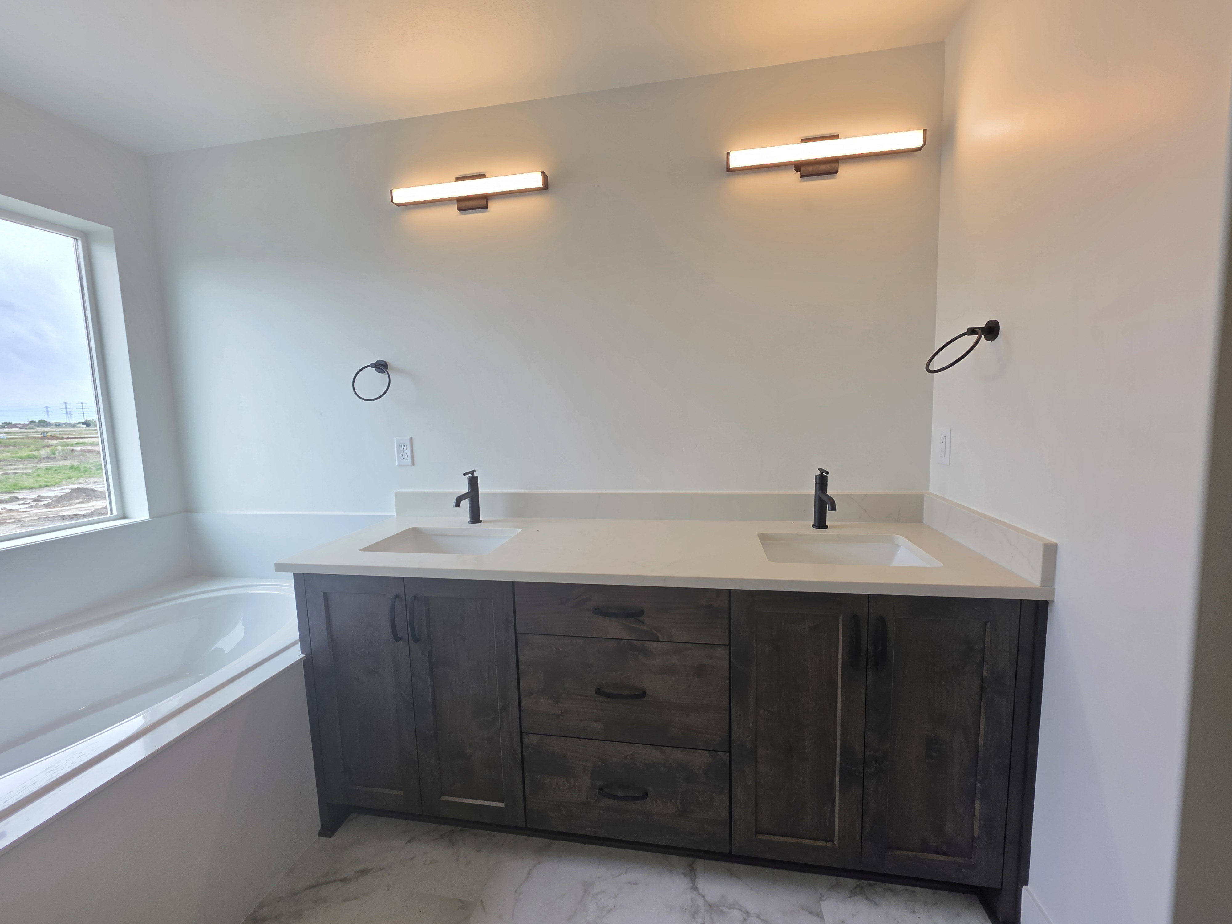 Double vanity featuring dark wood-finish cabinetry, integrated sinks, and light-toned countertops