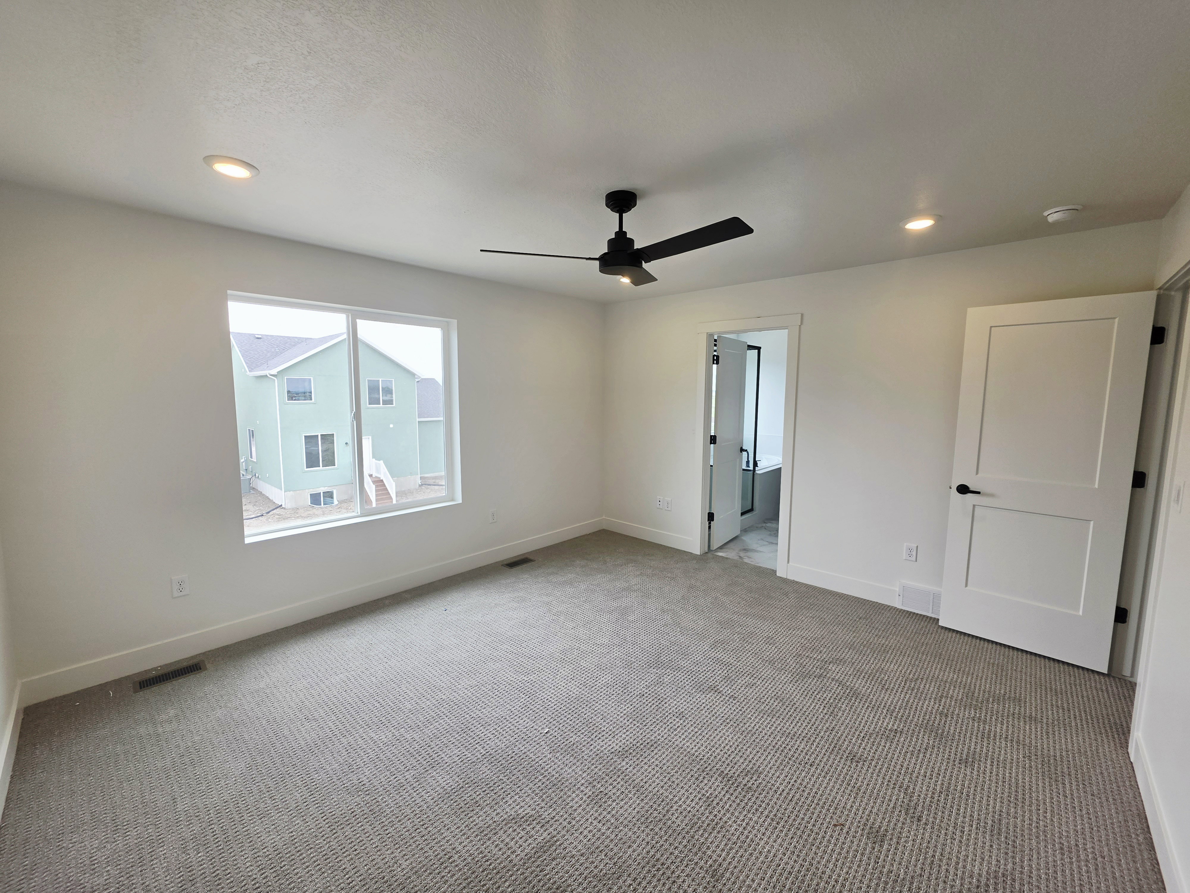 Spacious room featuring neutral carpeting, recessed lighting, and a modern ceiling fan