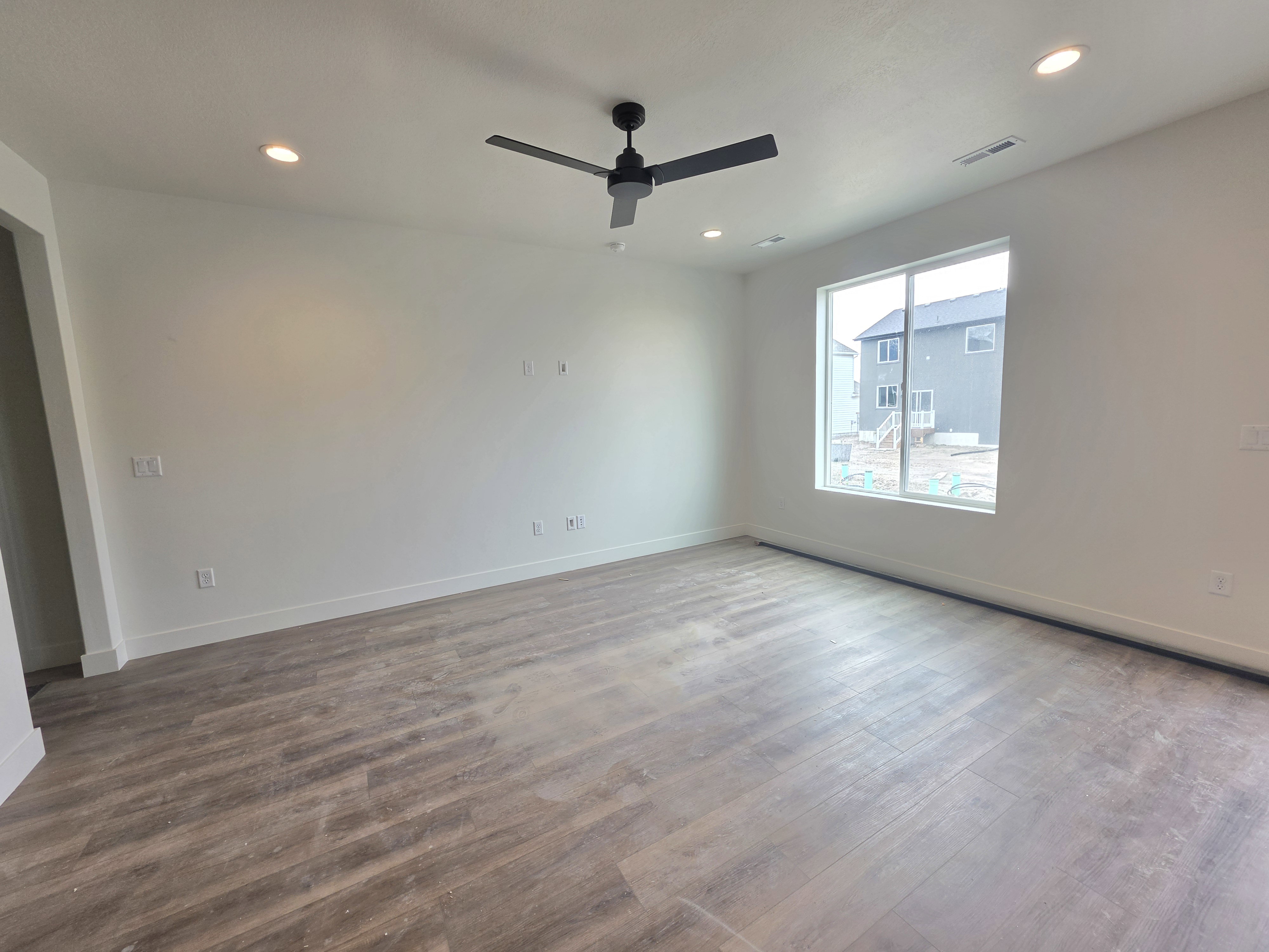 Spacious room featuring wood-finish flooring, a contemporary ceiling fan, recessed lighting, and a large window