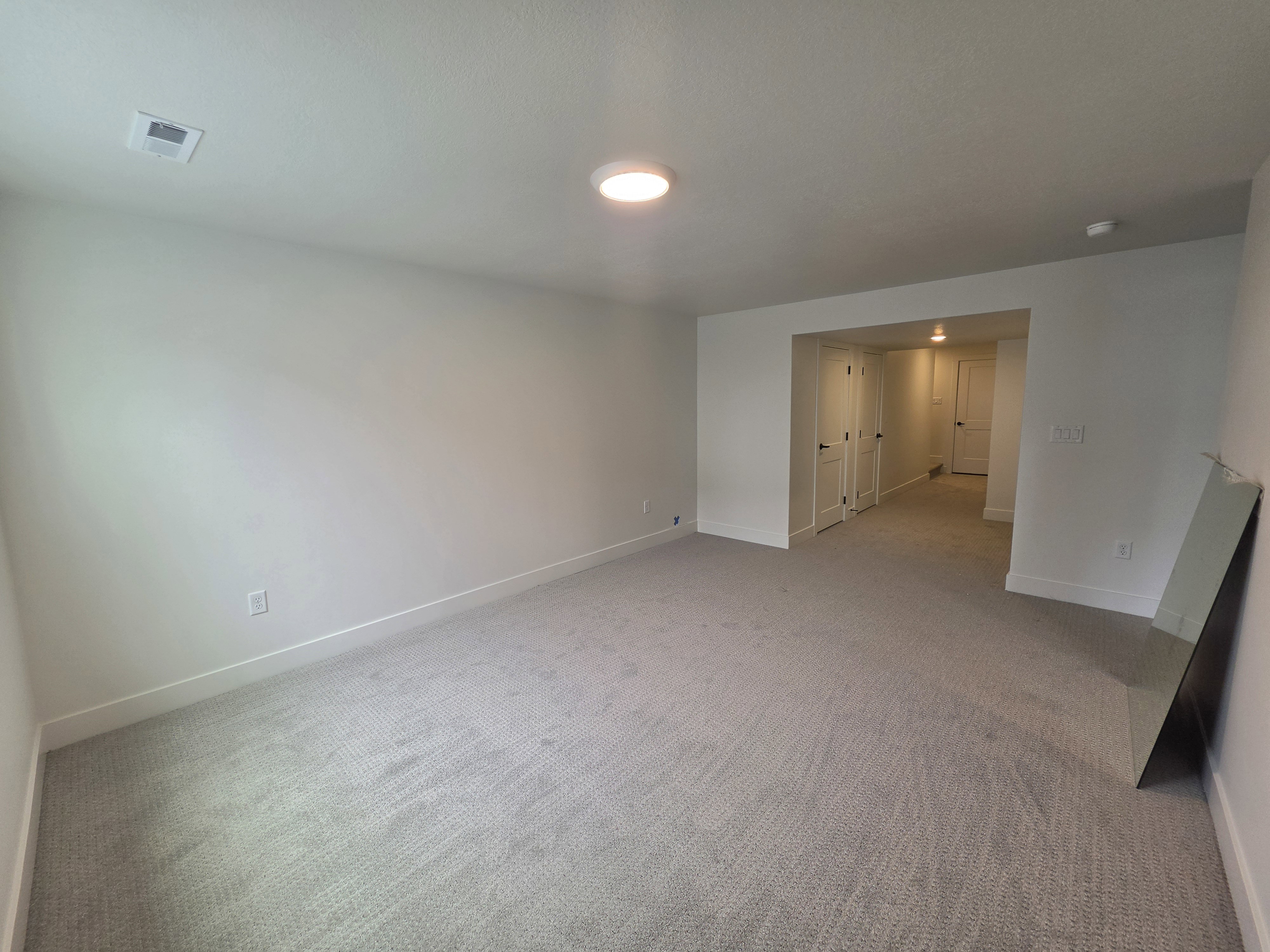 Spacious room featuring light gray carpeting, white painted walls, and white baseboards