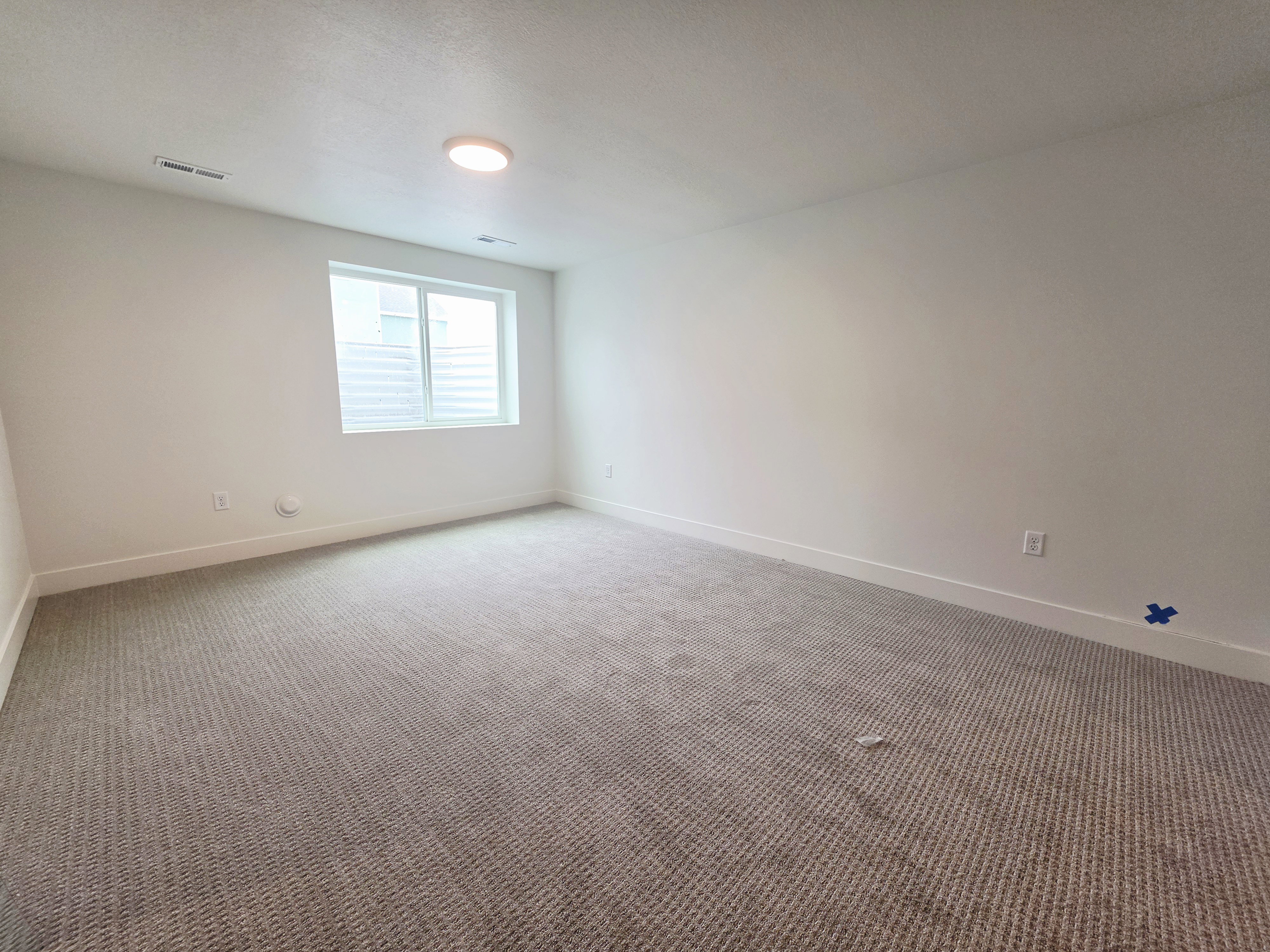 Carpeted room featuring a single window with horizontal blinds, a flush-mount ceiling light, and white baseboards
