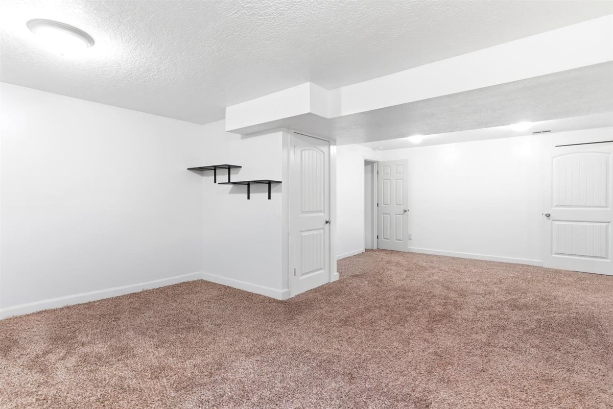 Spacious room featuring neutral carpeting, white walls, and bright overhead lighting