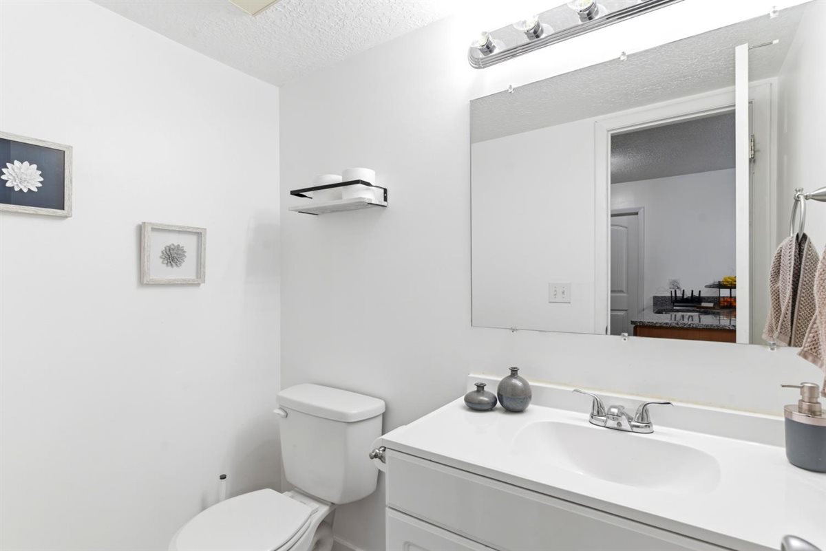 Bathroom featuring a white vanity with integrated sink, chrome faucet, and a large wall-mounted mirror with overhead bar lighting