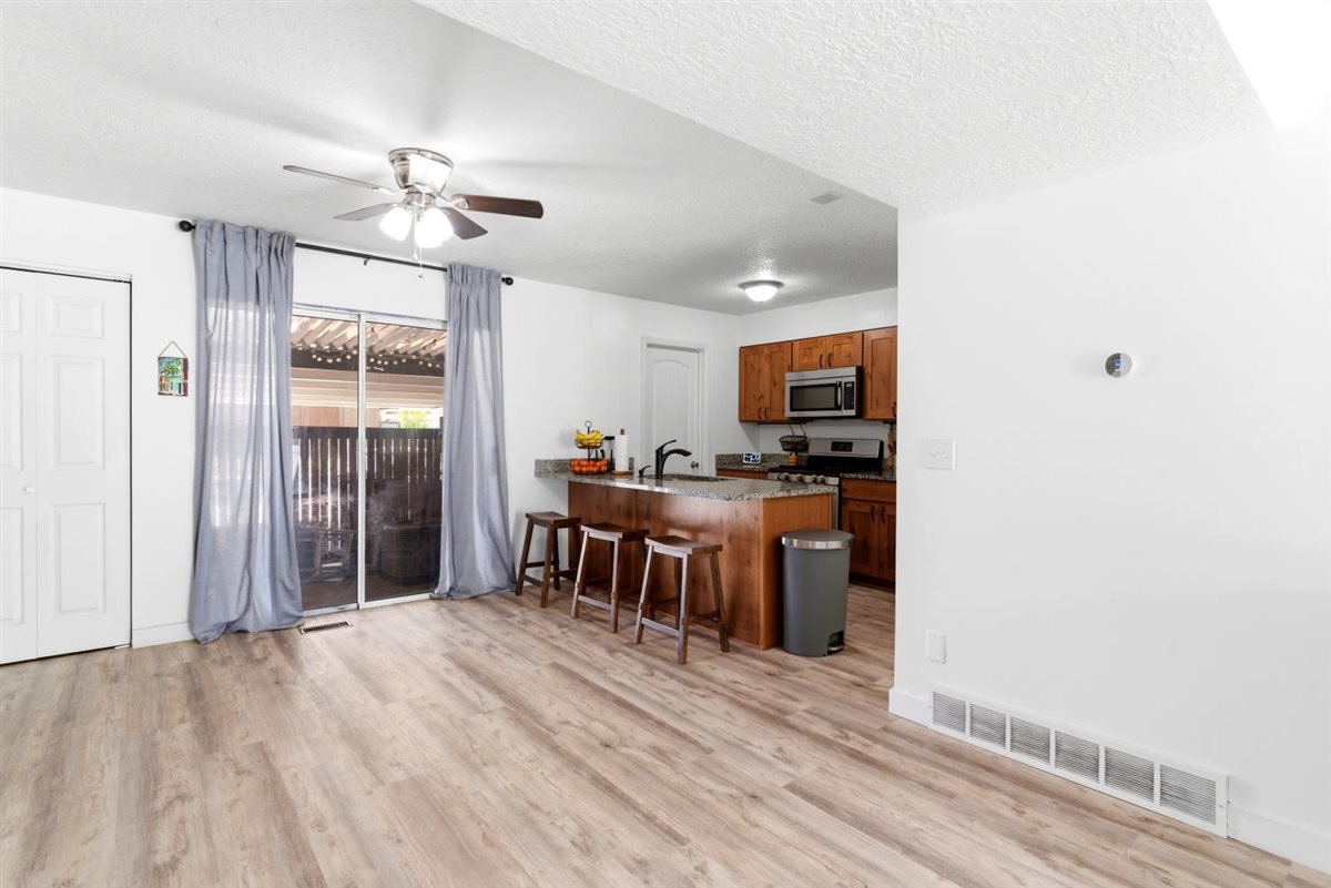 Open-concept living space featuring wood-finish flooring, a ceiling fan, and sliding glass doors