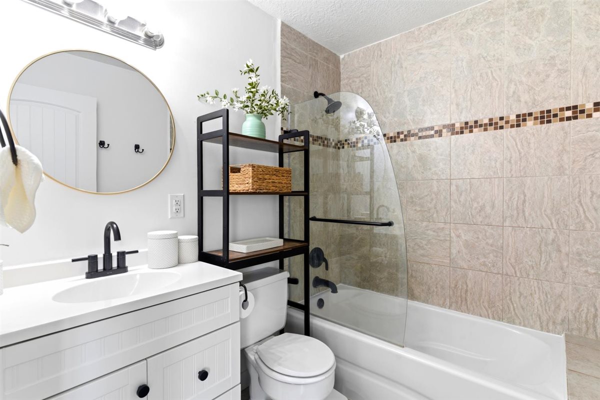 White vanity with black hardware, matte black faucet, and a circular mirror