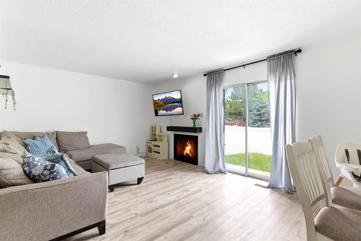 Spacious living area featuring light wood-finish flooring, a contemporary fireplace with a dark mantel, and recessed lighting