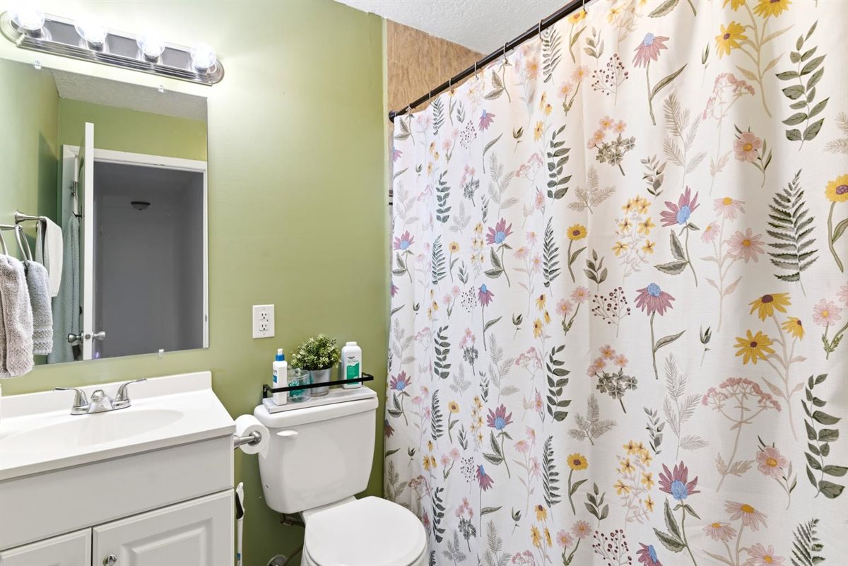 Bathroom featuring a white vanity with integrated sink, chrome faucet, wall-mounted mirror, and overhead light fixture