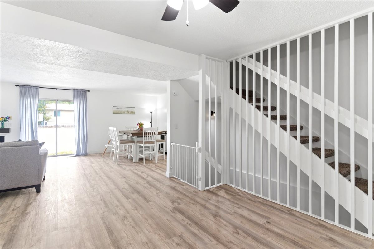 Open-concept living space with wood-finish flooring, white walls, and a ceiling fan