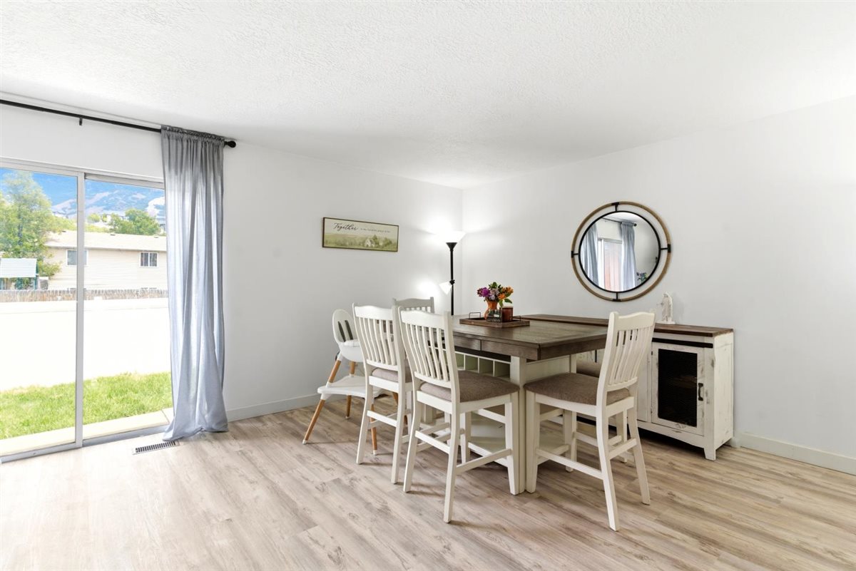 Dining area featuring light wood-finish flooring, white walls, and a sliding glass door