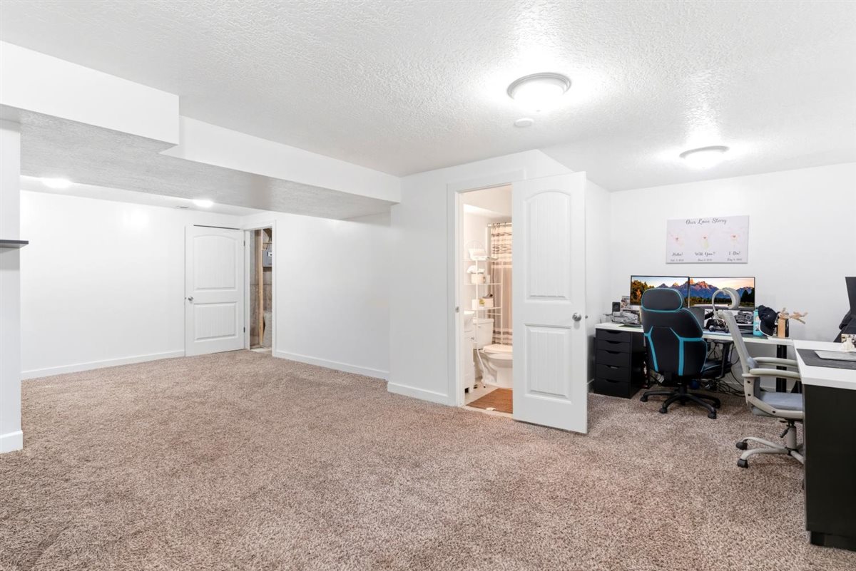 Spacious room featuring neutral carpeting, recessed lighting, and a white interior door