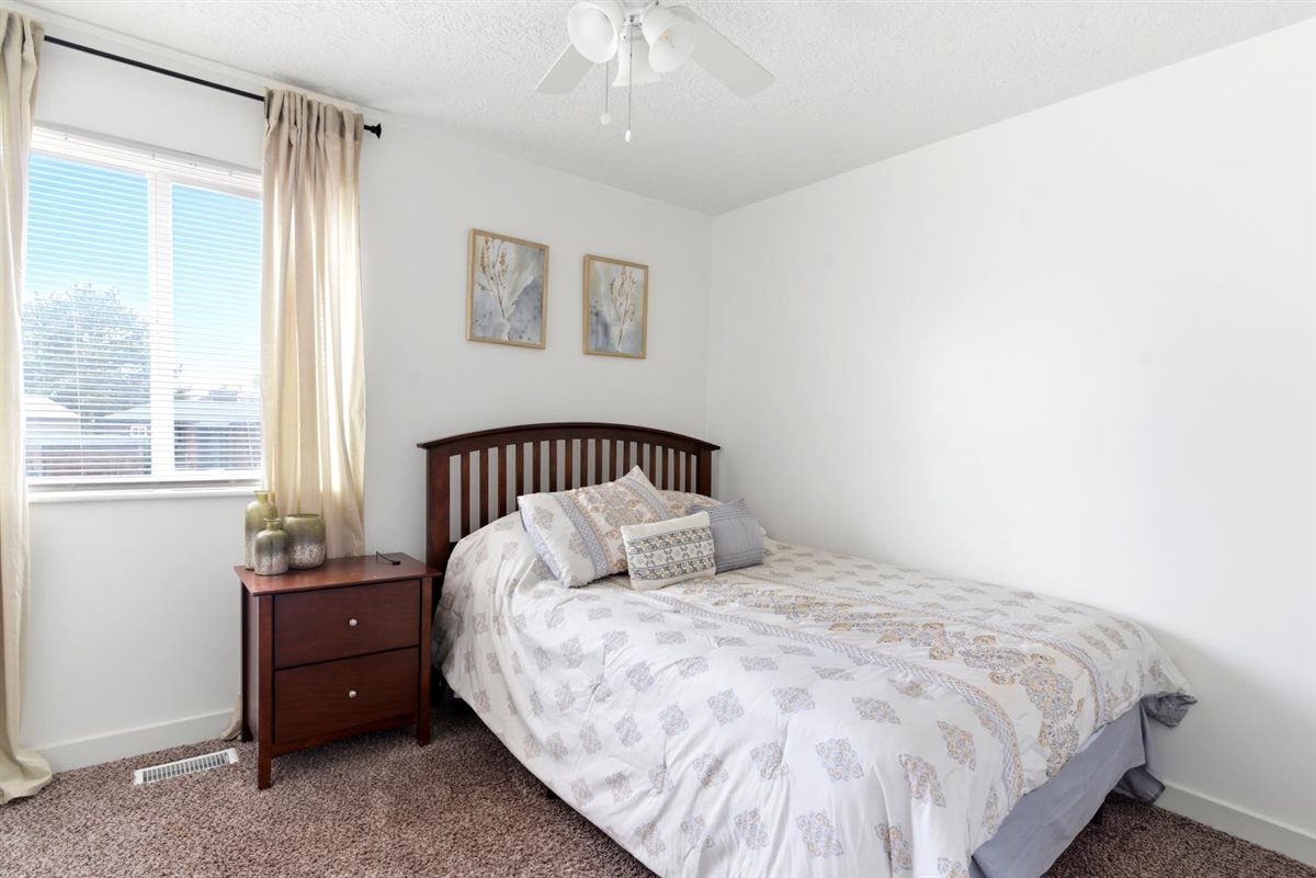 Bedroom featuring a window with horizontal blinds and drapes, white walls, and a ceiling fan
