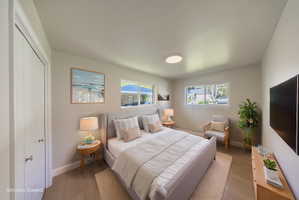 Spacious room featuring light wood-finish flooring, two large windows, a ceiling-mounted light fixture, and two panel doors