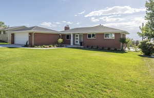 Brick exterior with a white garage door, concrete driveway, and established landscaping