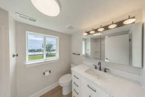 Modern bathroom featuring a white vanity with black hardware, an undermount sink, and a large mirror with a five-light fixture