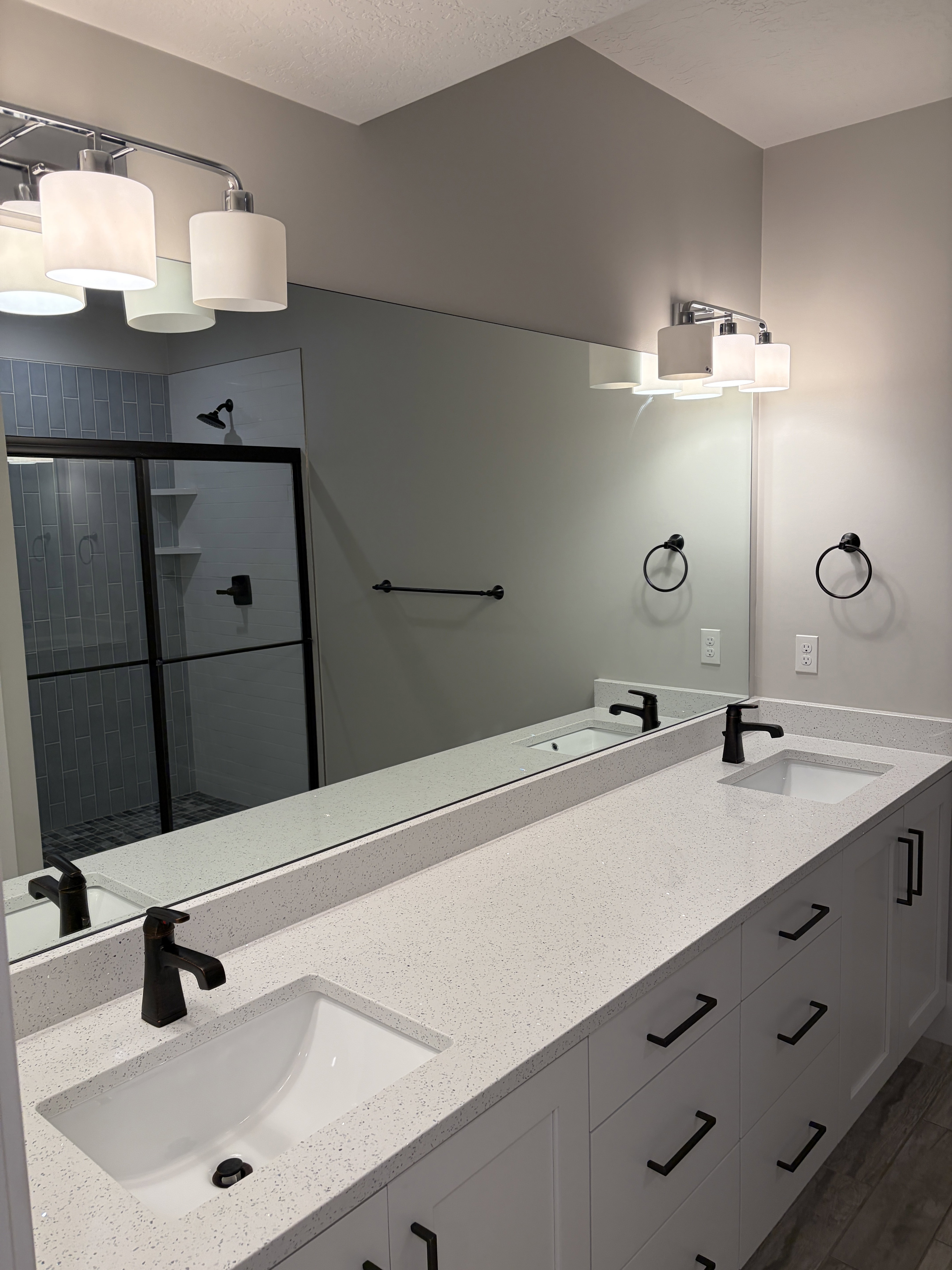 Dual vanity with a white speckled countertop, undermount sinks, and matte black fixtures