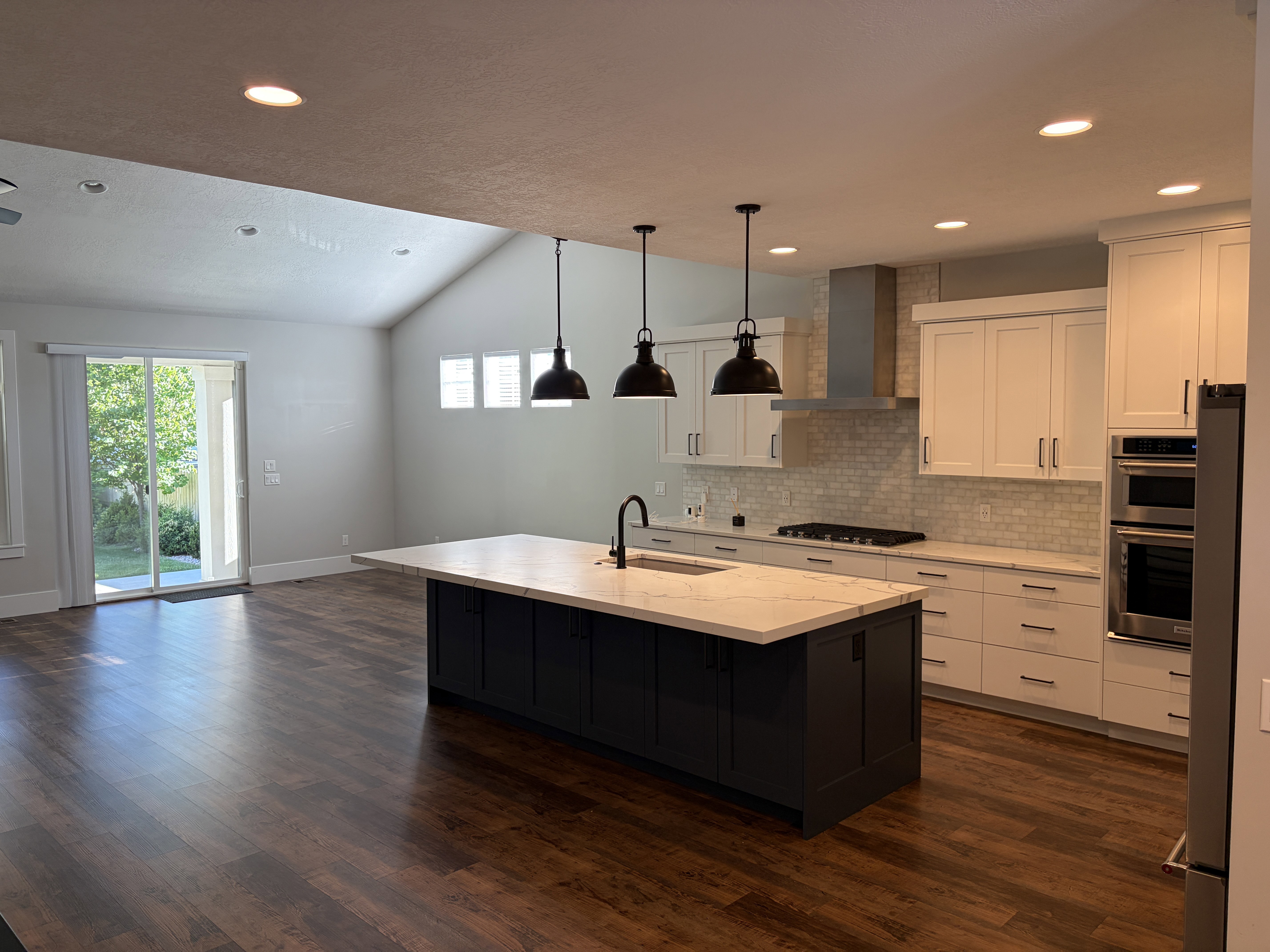 Open-concept living space with wood-finish flooring, a vaulted ceiling, and recessed lighting