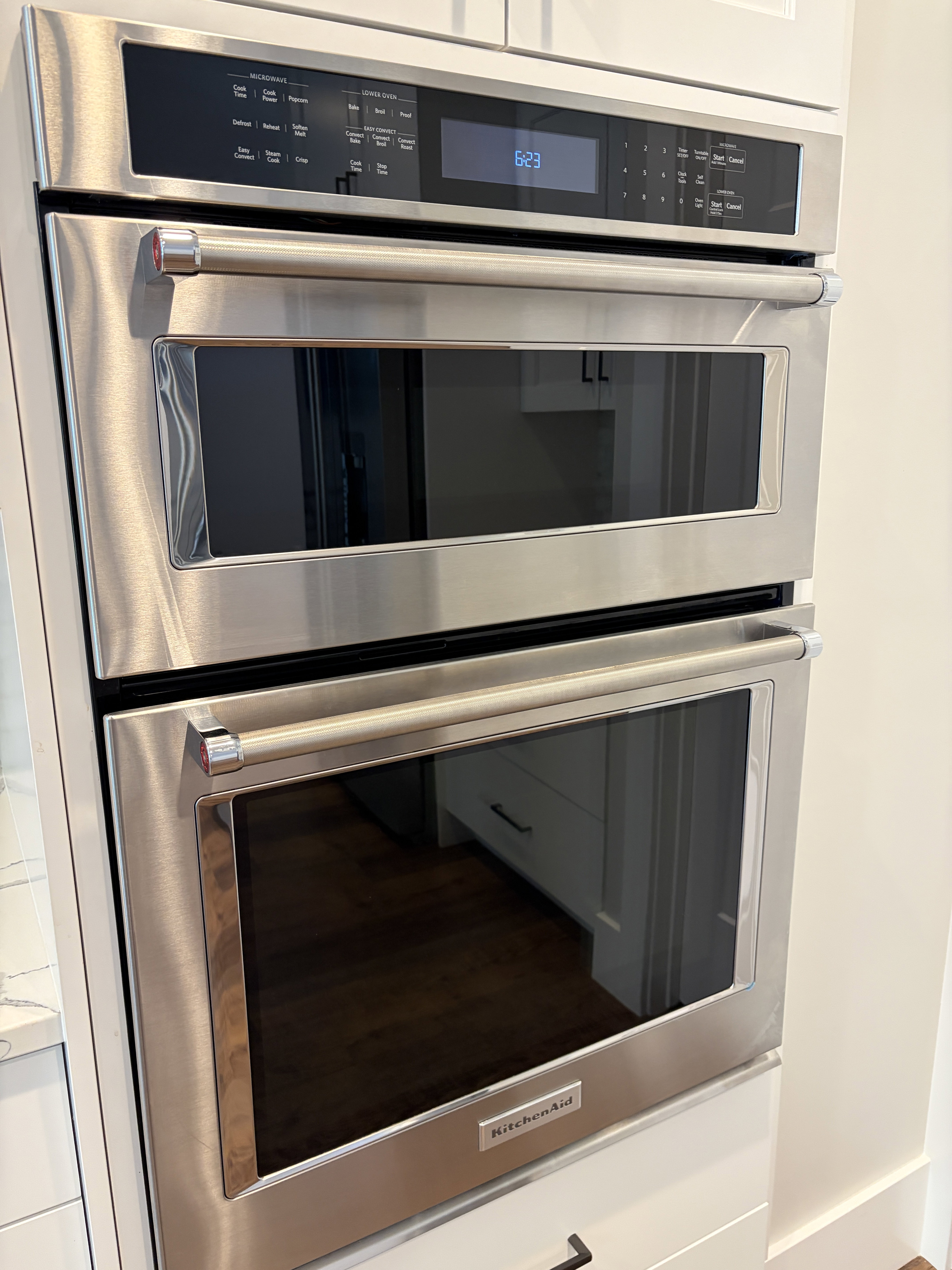 Built-in stainless steel double oven with a digital display, integrated into white cabinetry