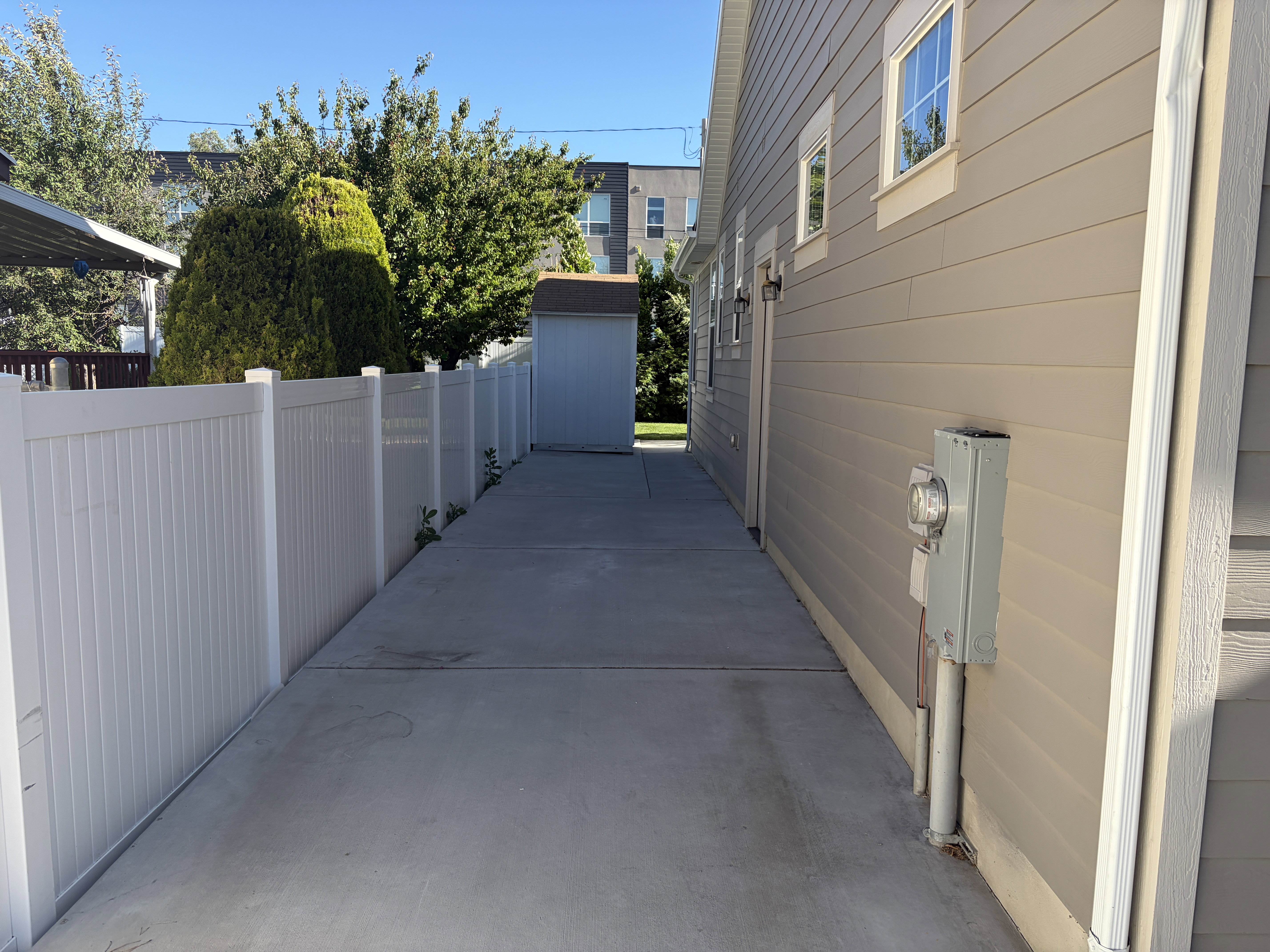 Concrete walkway bordered by a white privacy fence