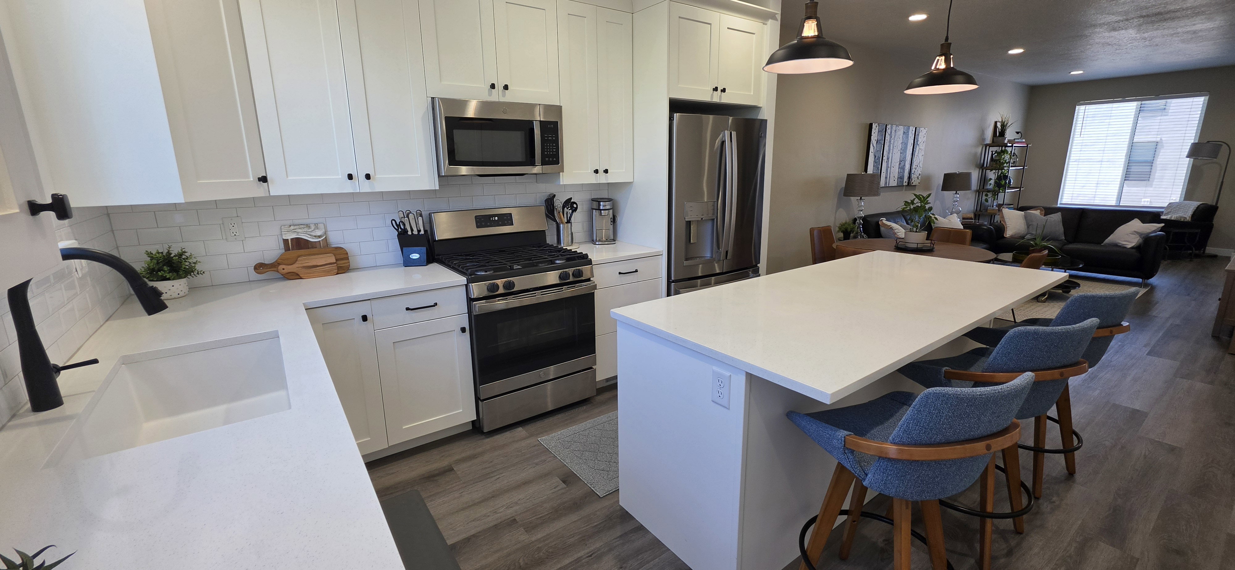 Contemporary kitchen featuring white shaker cabinetry, stainless steel appliances, white subway tile backsplash, white countertops, and wood-finish flooring