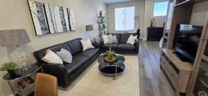 Open-concept living space featuring wood-finish flooring, neutral wall tones, and ample natural light from a large window