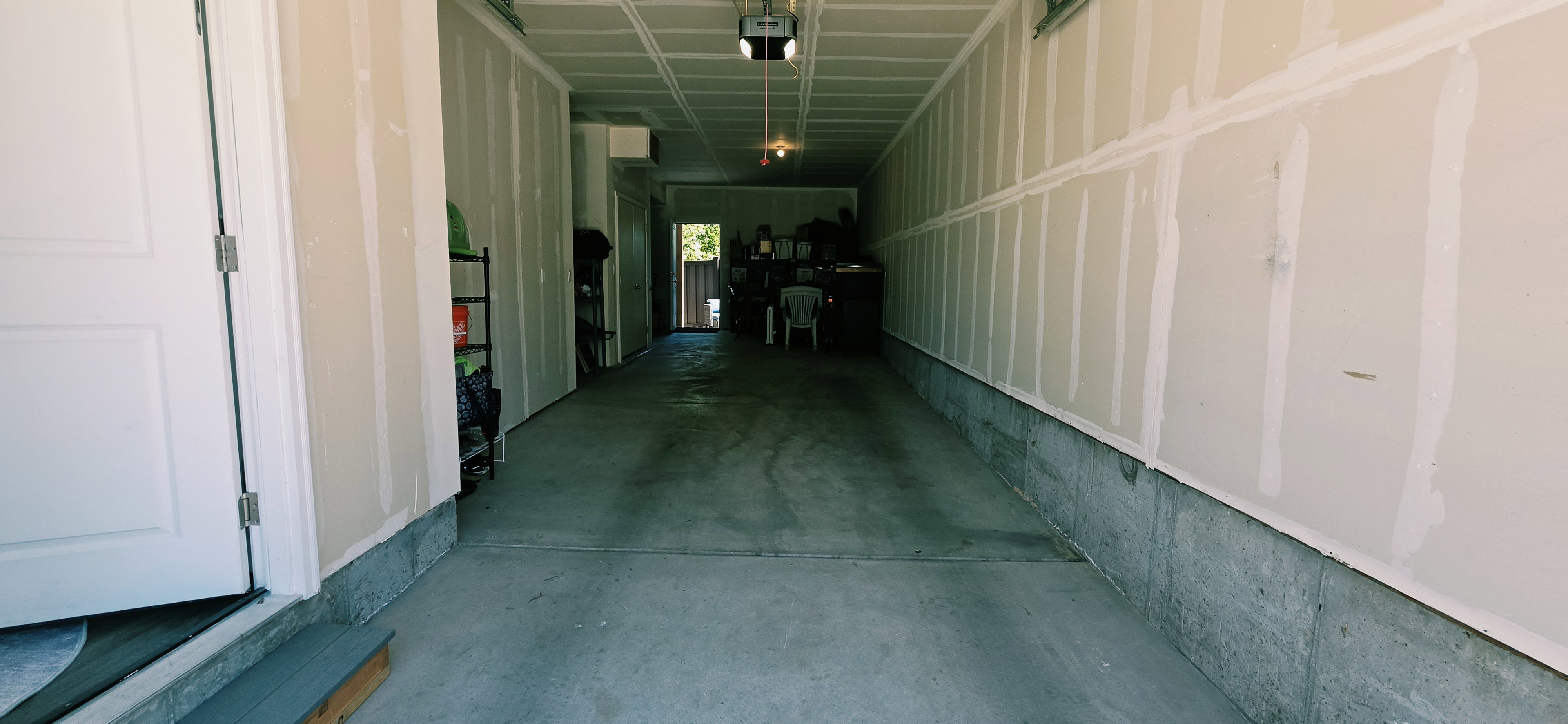 Spacious garage featuring a concrete floor, exposed drywall walls, and overhead lighting