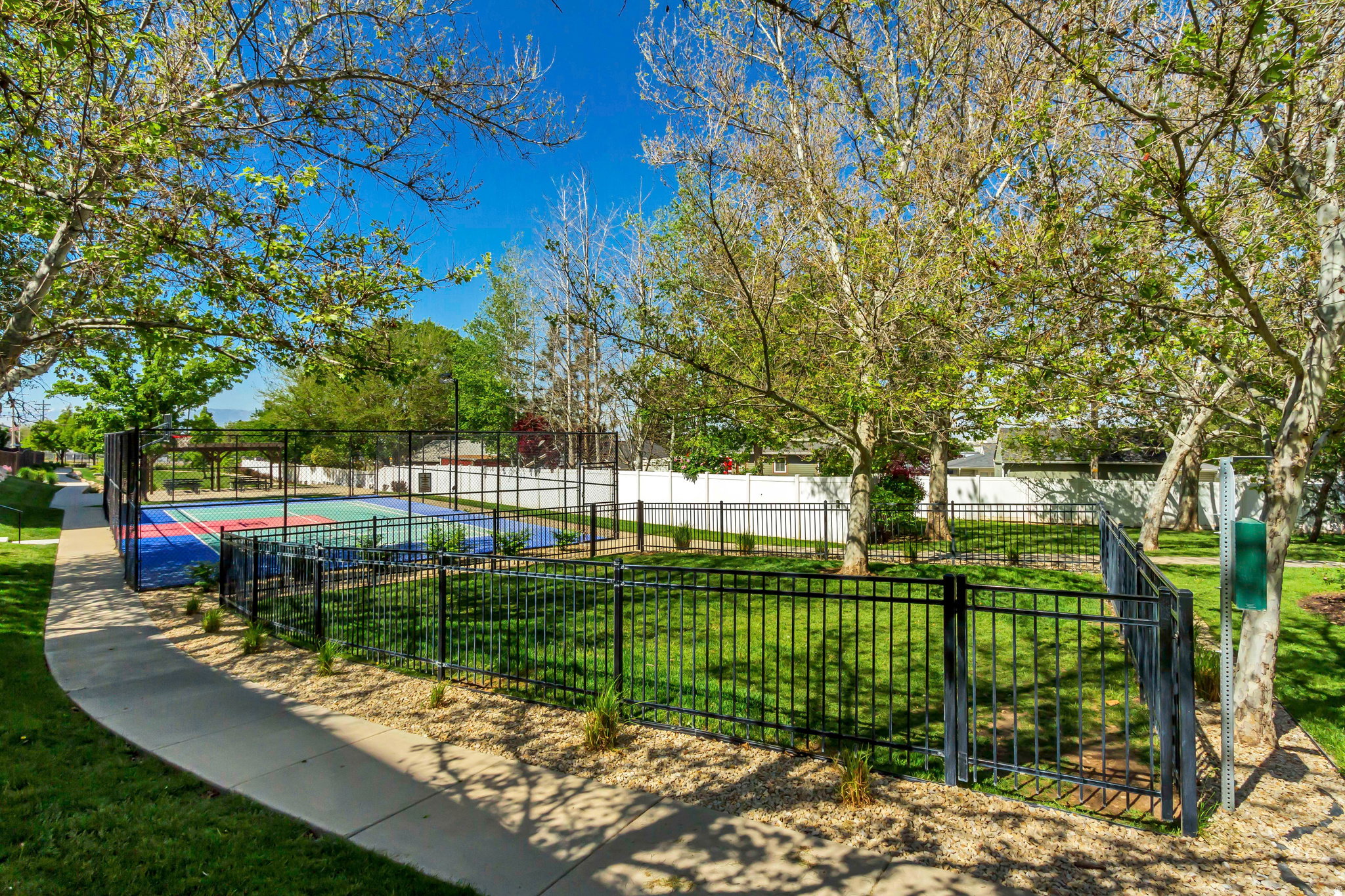 Multi-sport court with vibrant blue, red, and green surfacing, enclosed by black chain-link fencing