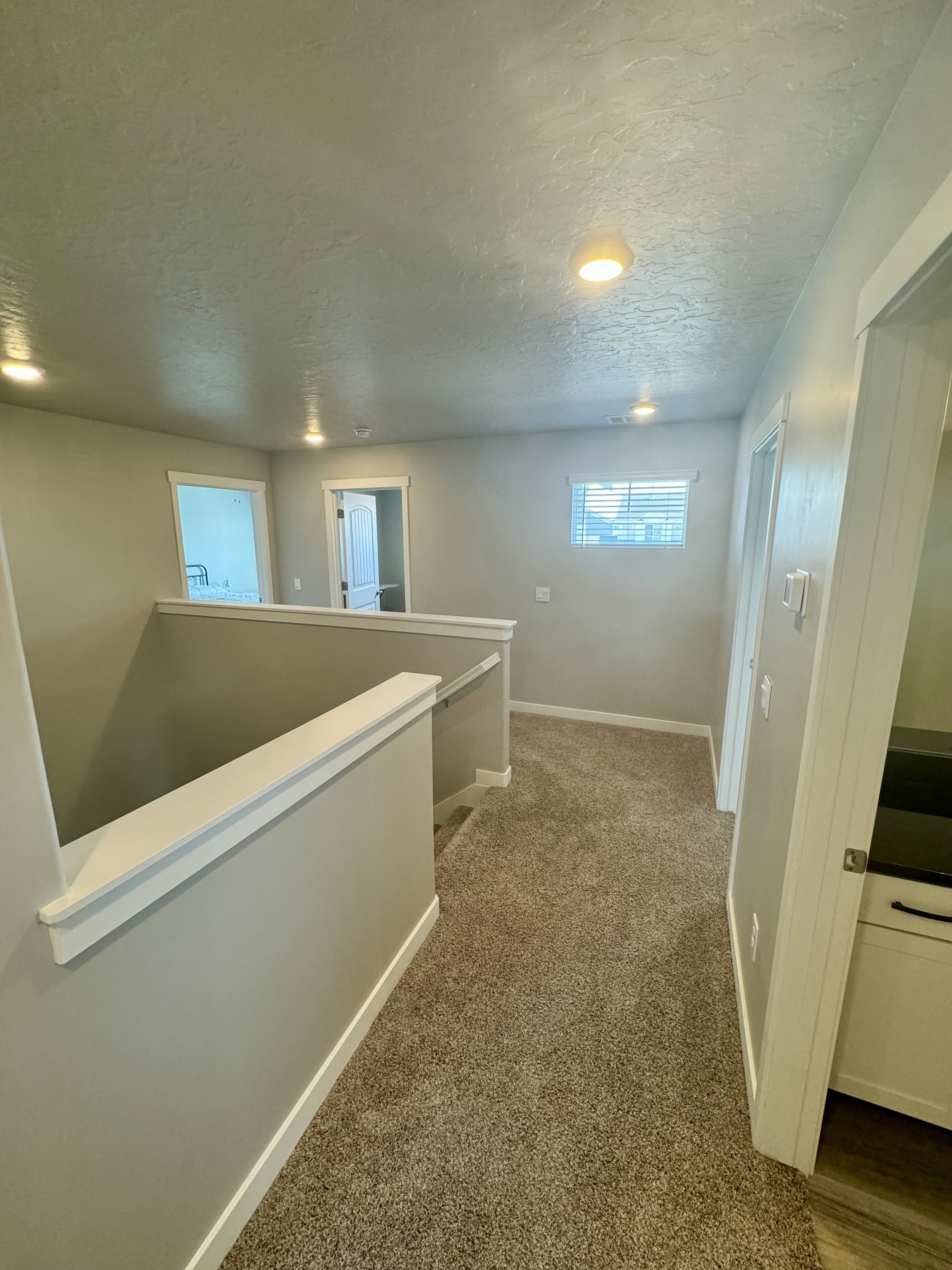 Second-level hallway featuring neutral-toned carpeting, recessed lighting, and a window with blinds