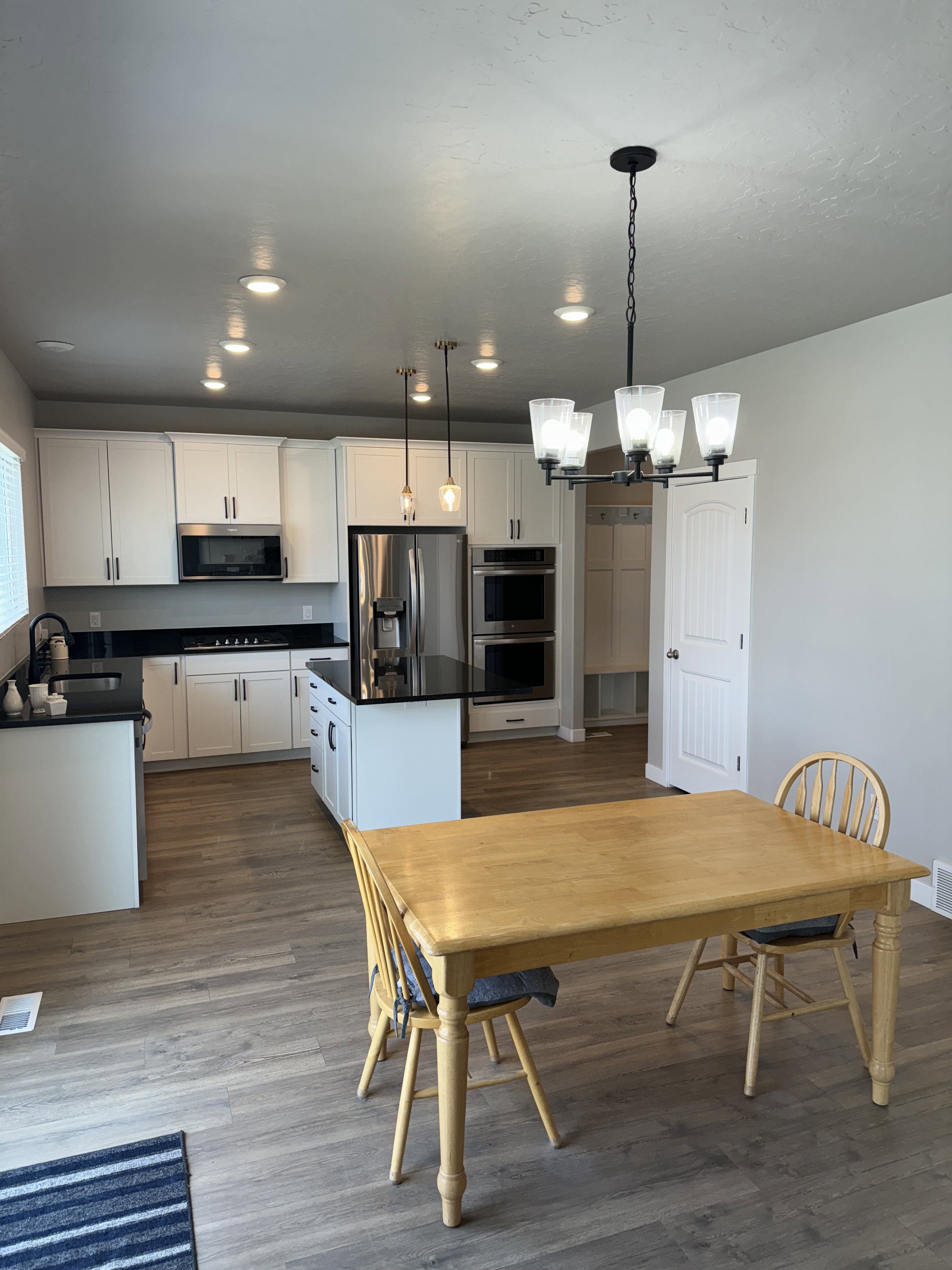 Modern kitchen featuring white cabinetry, black countertops, stainless steel appliances, and a central island