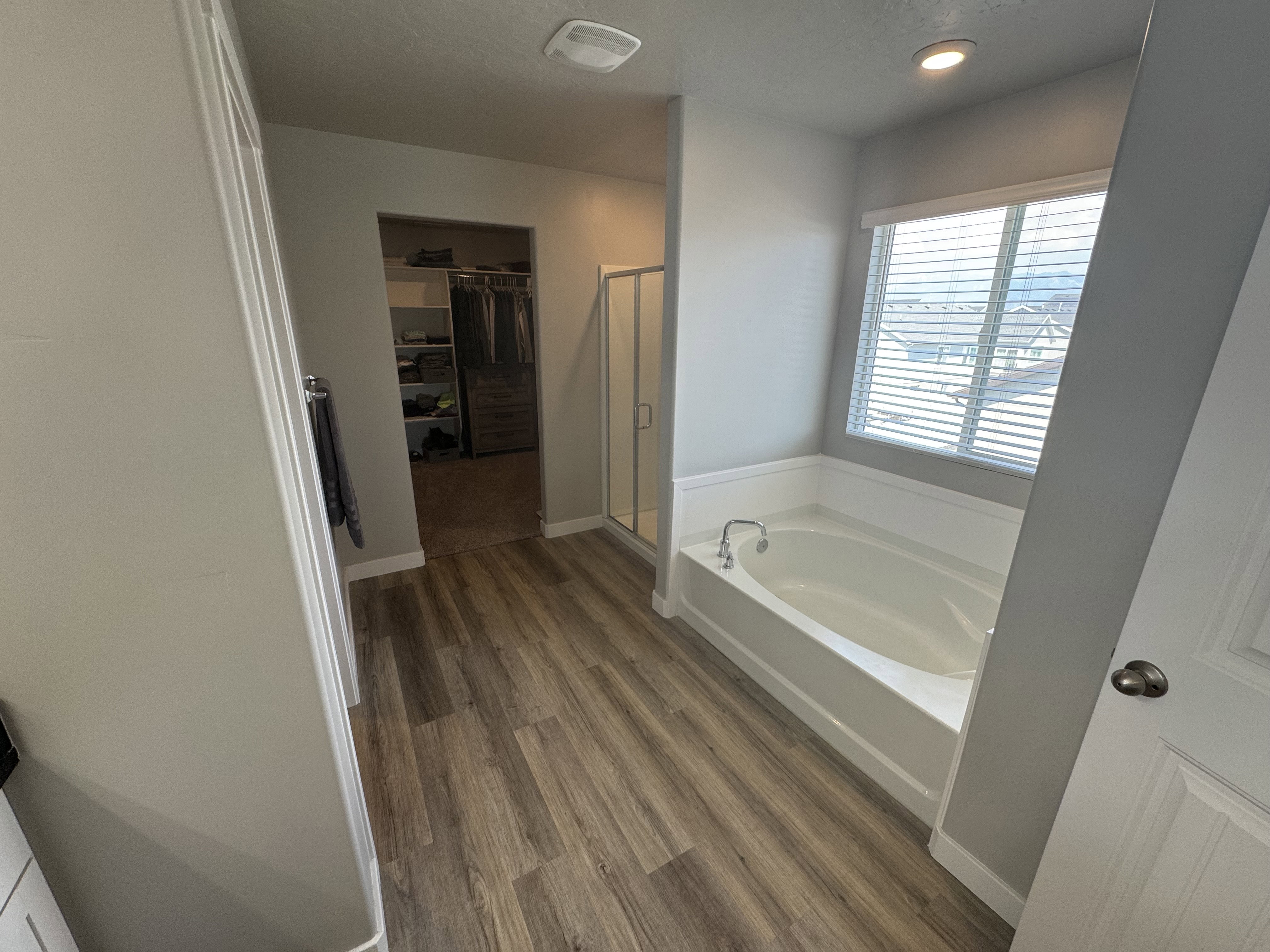 Bathroom featuring an integrated soaking tub with white wainscoting and a window with blinds