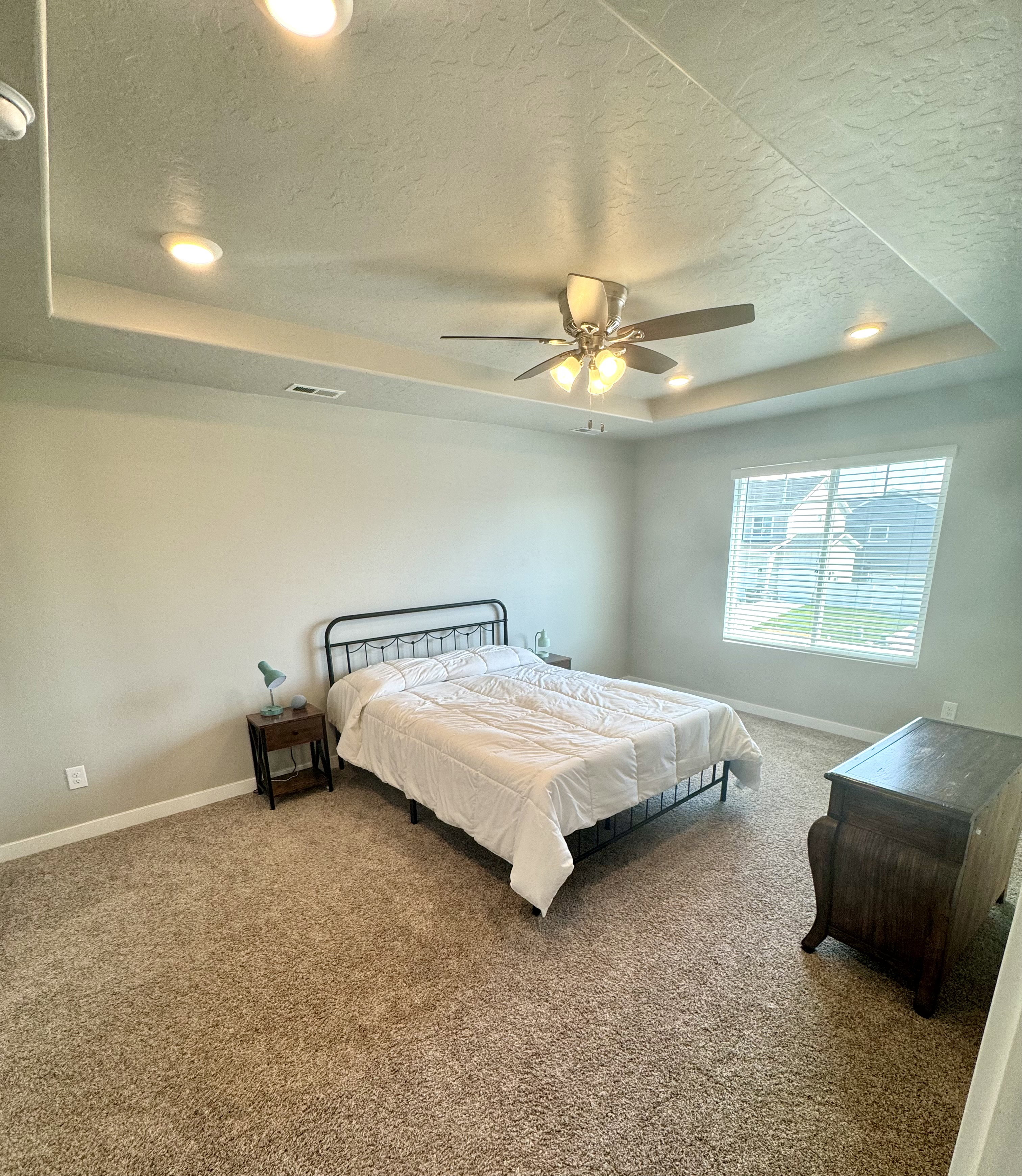 Spacious room featuring a tray ceiling with recessed lighting and a ceiling fan