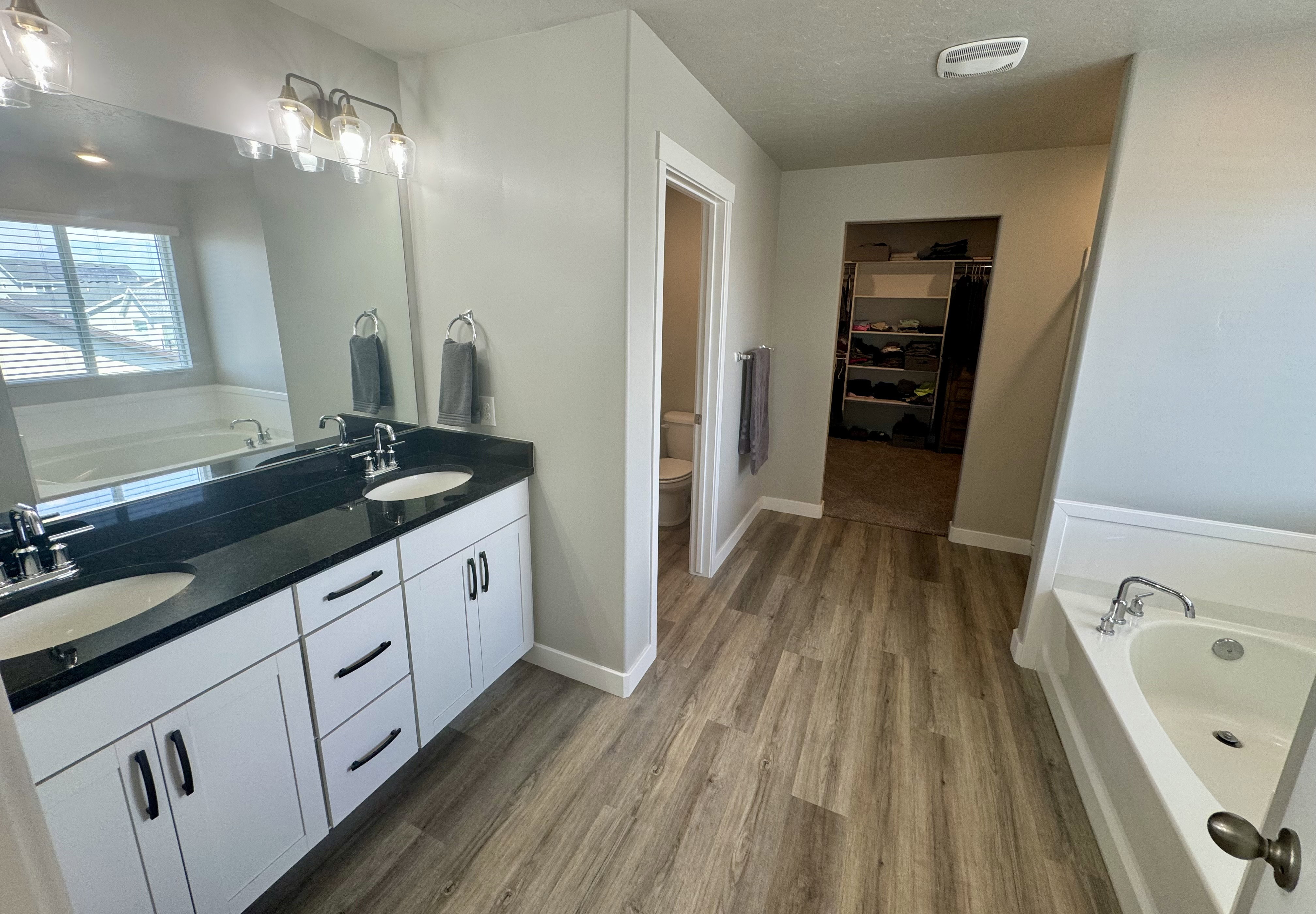 Dual vanity featuring white cabinetry, black countertops, and undermount sinks