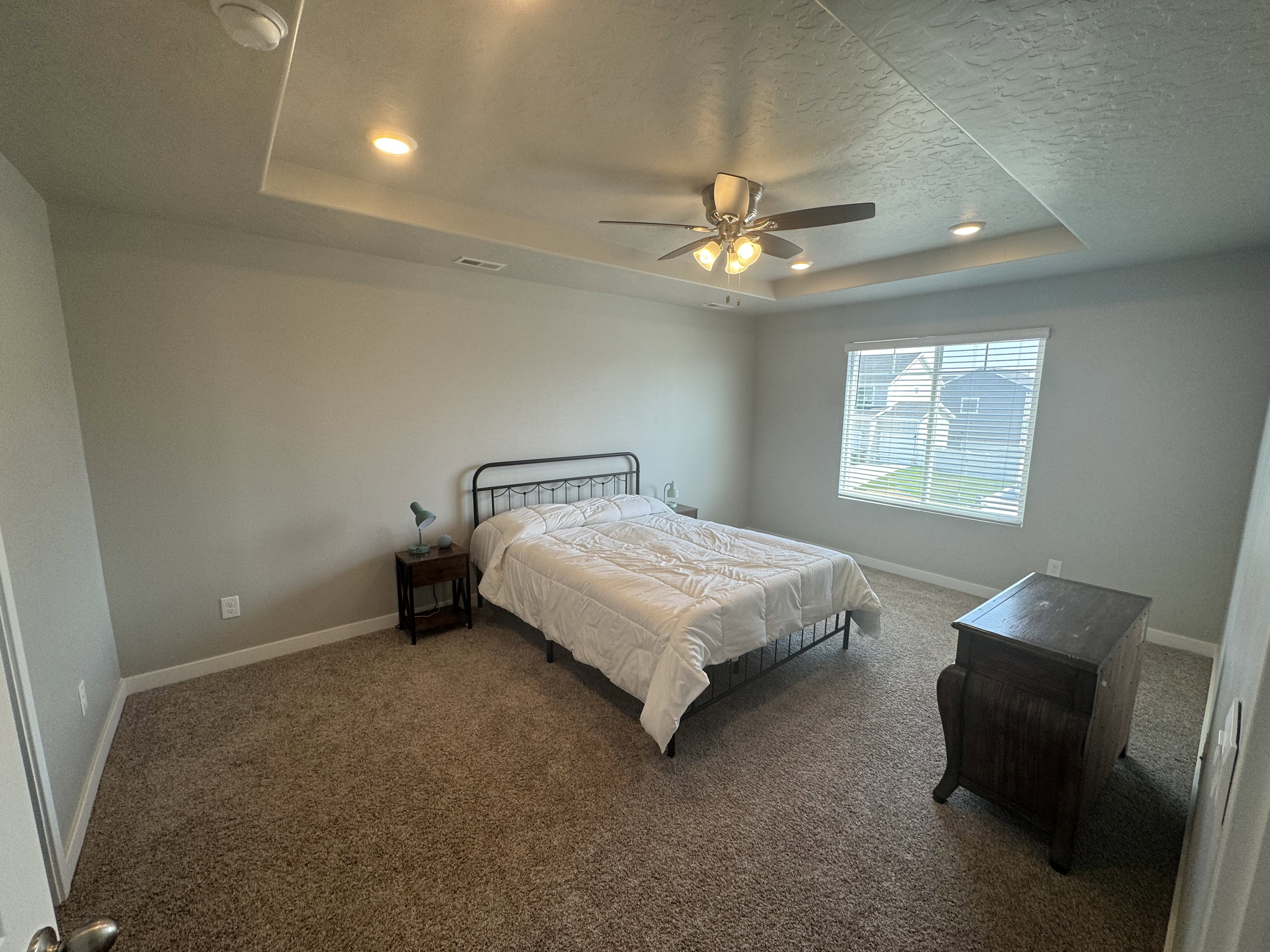 Carpeted room with a tray ceiling featuring recessed lighting and a ceiling fan