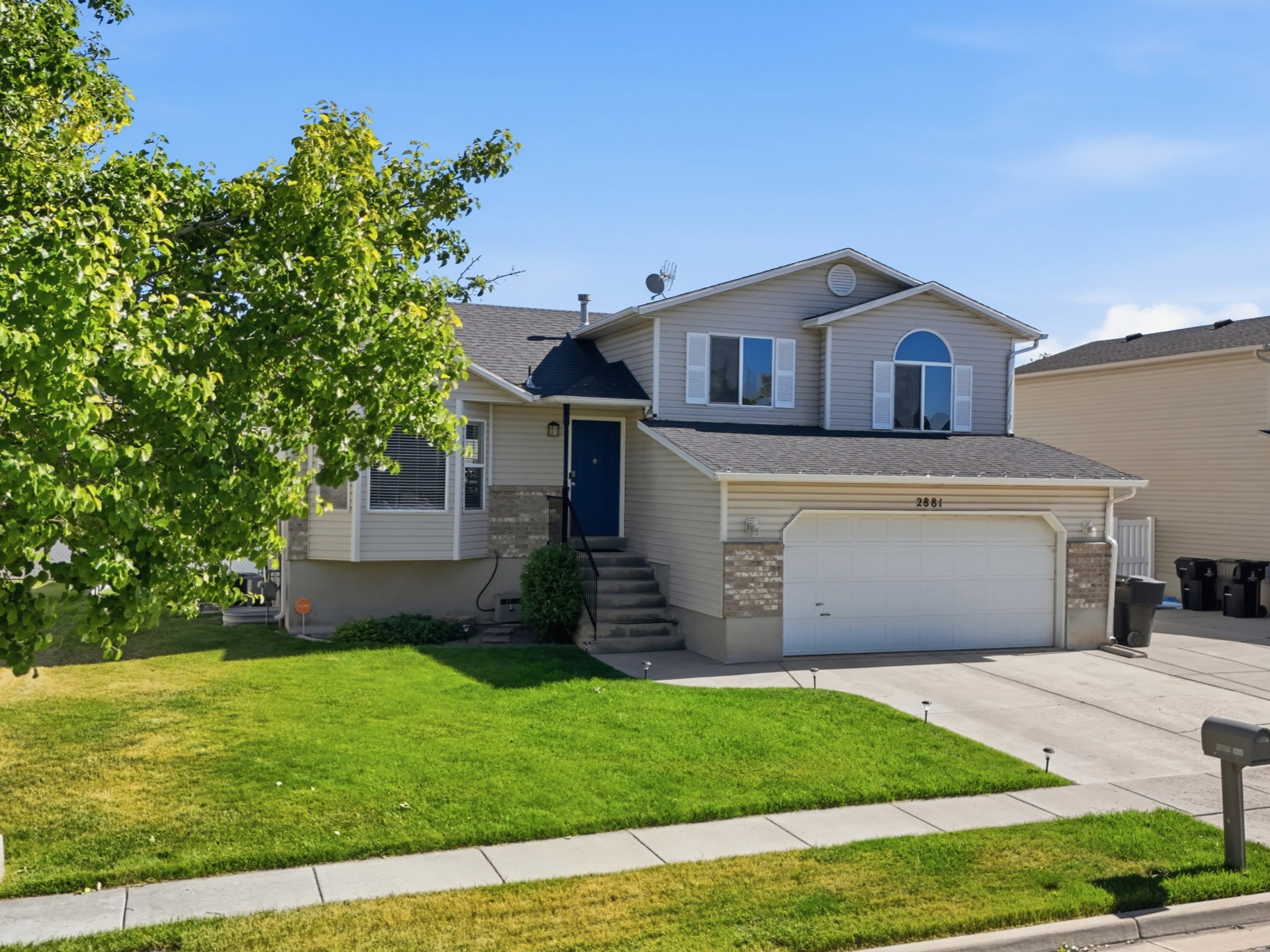 Two-story residence featuring a two-car garage, stone accents, and a vibrant green lawn