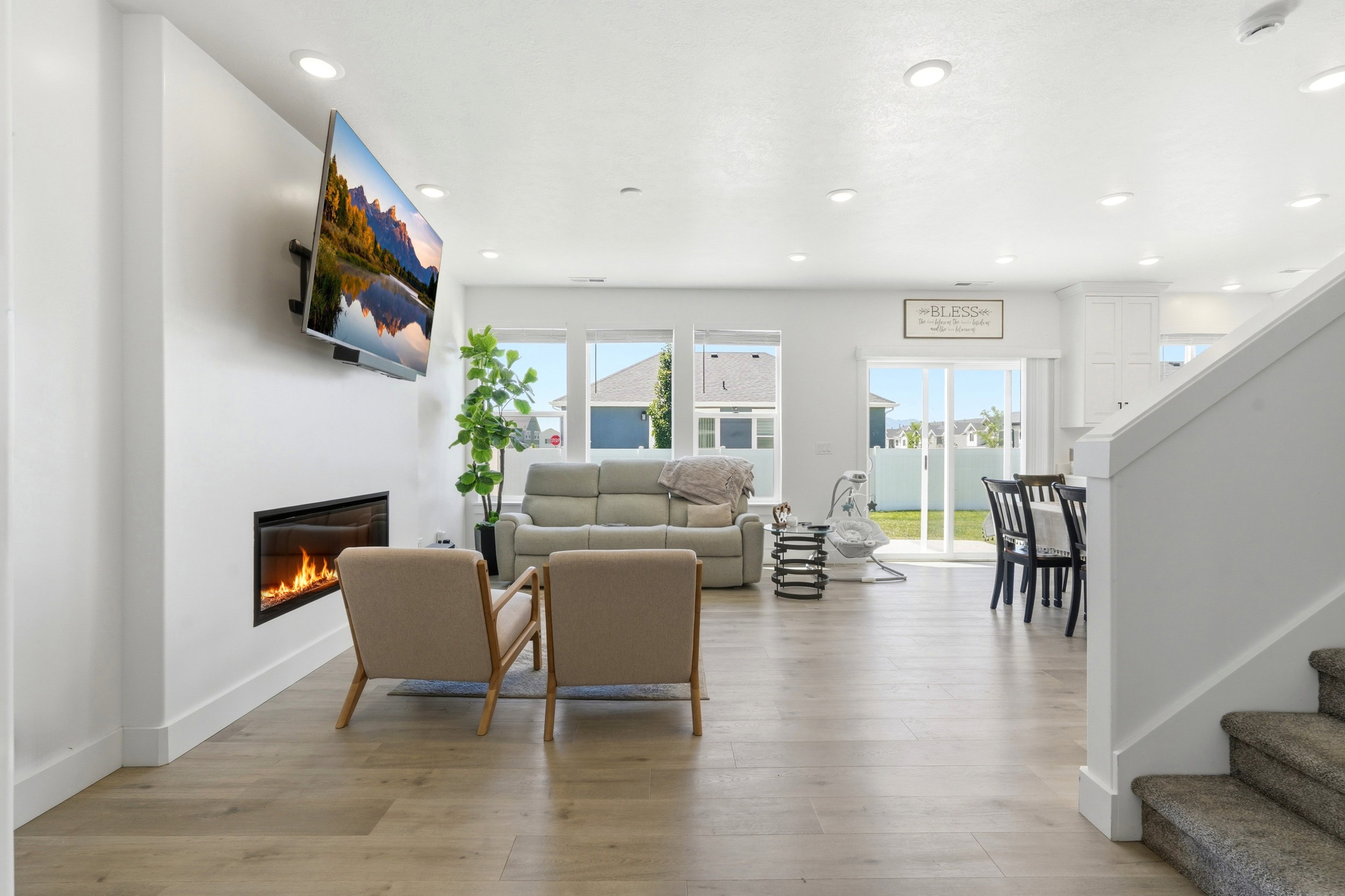 Open-concept living space with wood-finish flooring, recessed lighting, and a modern linear fireplace