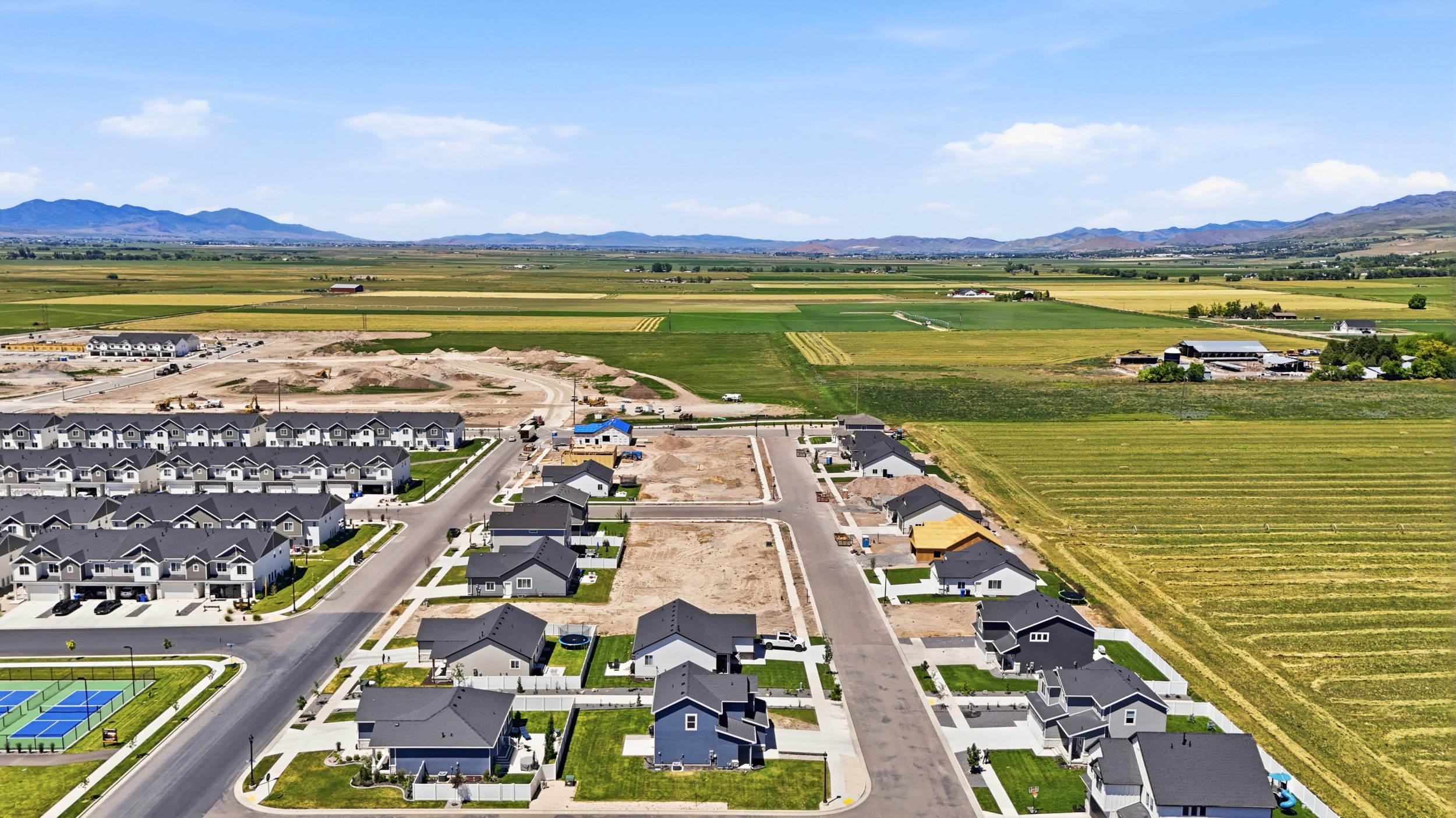 Aerial view of a developing residential community featuring single-family homes and townhomes