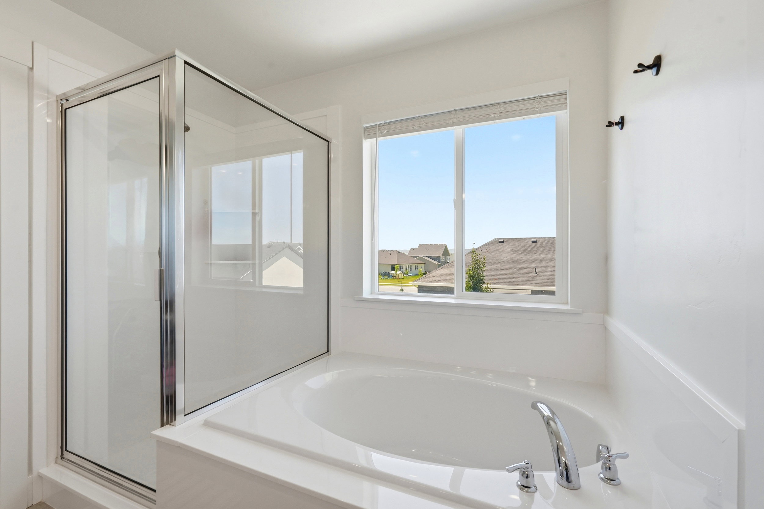 Built-in soaking tub with chrome fixtures, accompanied by a separate glass-enclosed shower