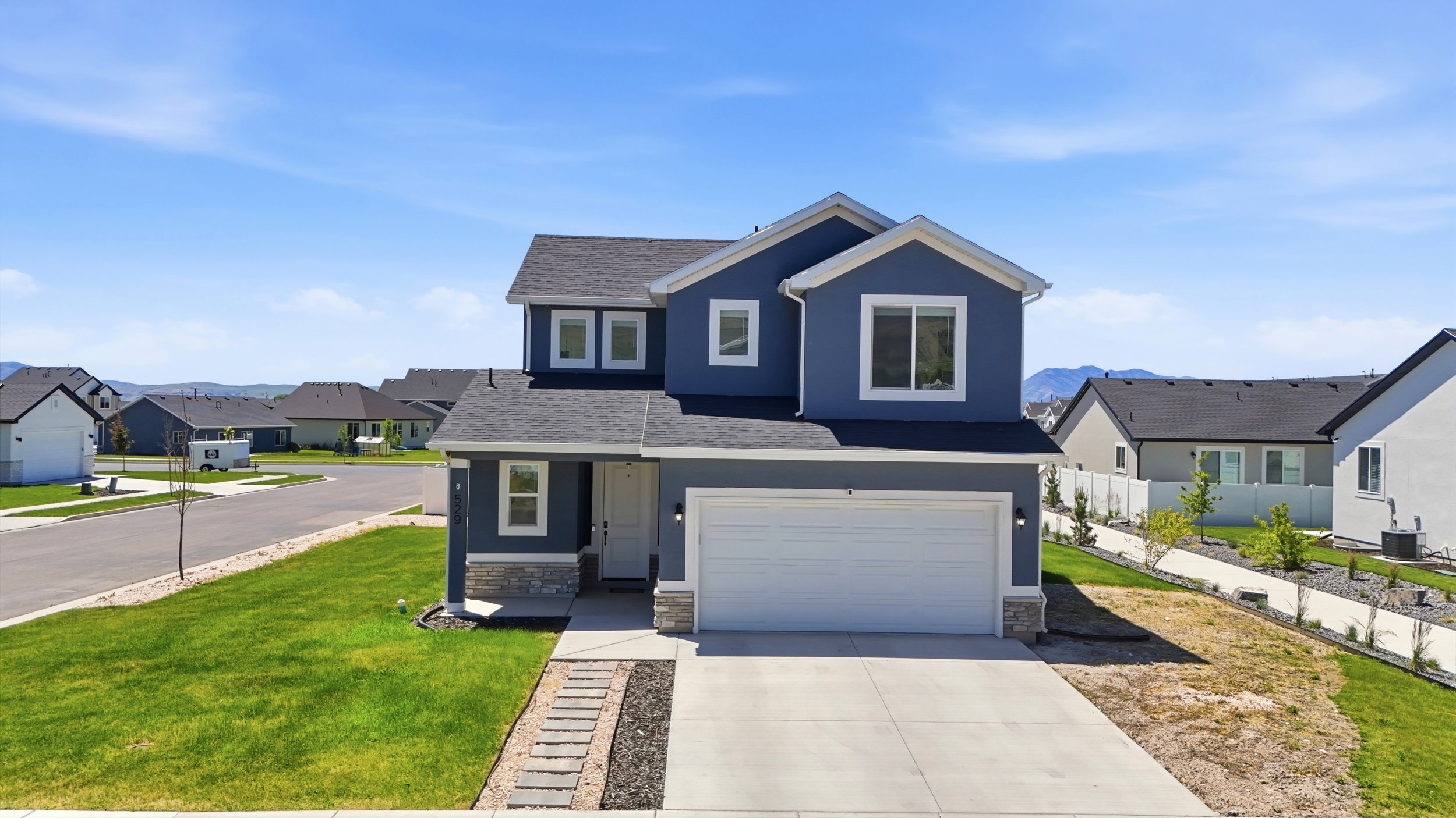 Two-story residence featuring a blue siding exterior with white trim accents and a stone facade foundation