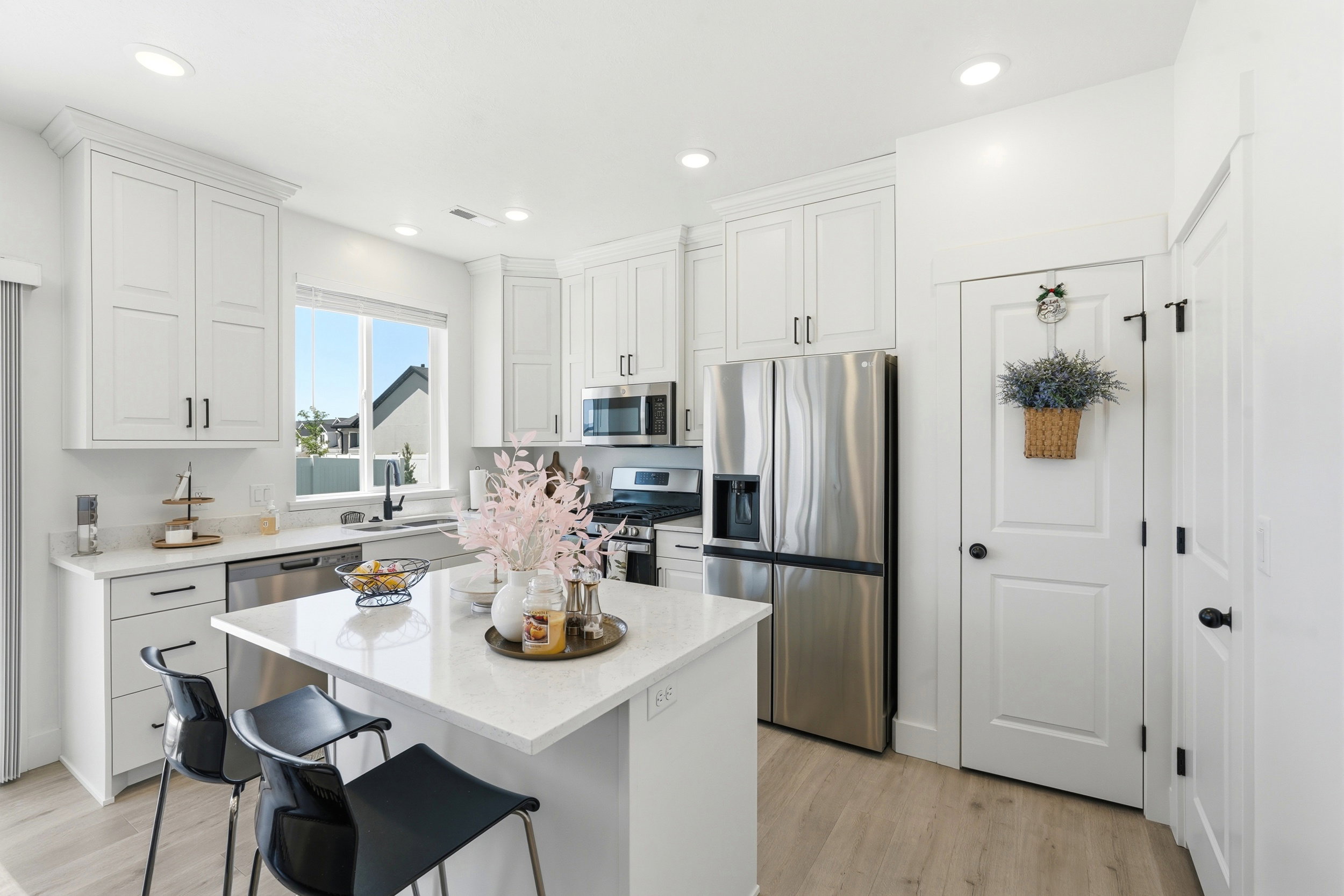 Contemporary kitchen featuring a center island, stainless steel appliances, light wood-finish flooring, white cabinetry, and recessed lighting