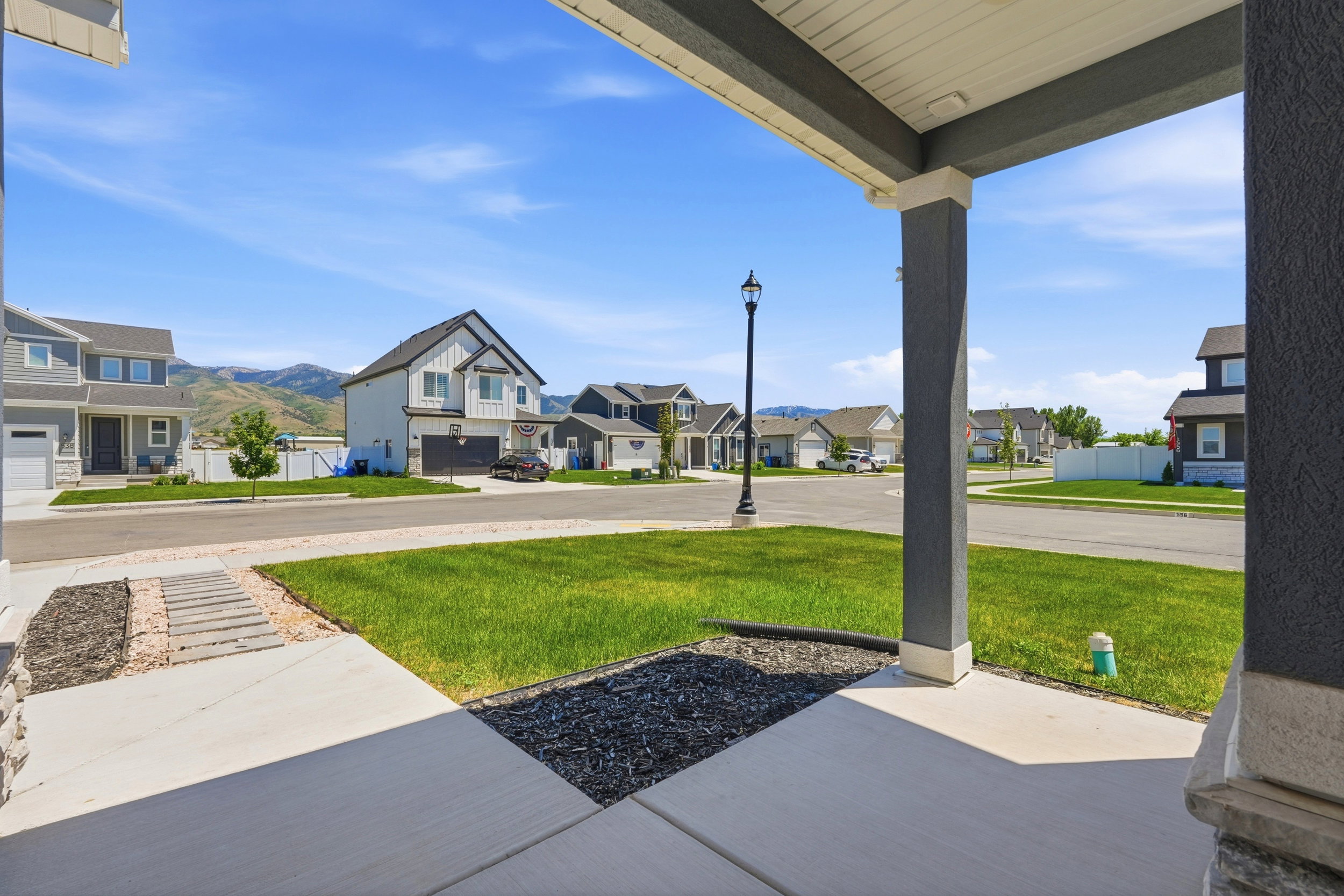 Front porch with a concrete walkway, decorative dark-colored rock landscaping, and a manicured lawn