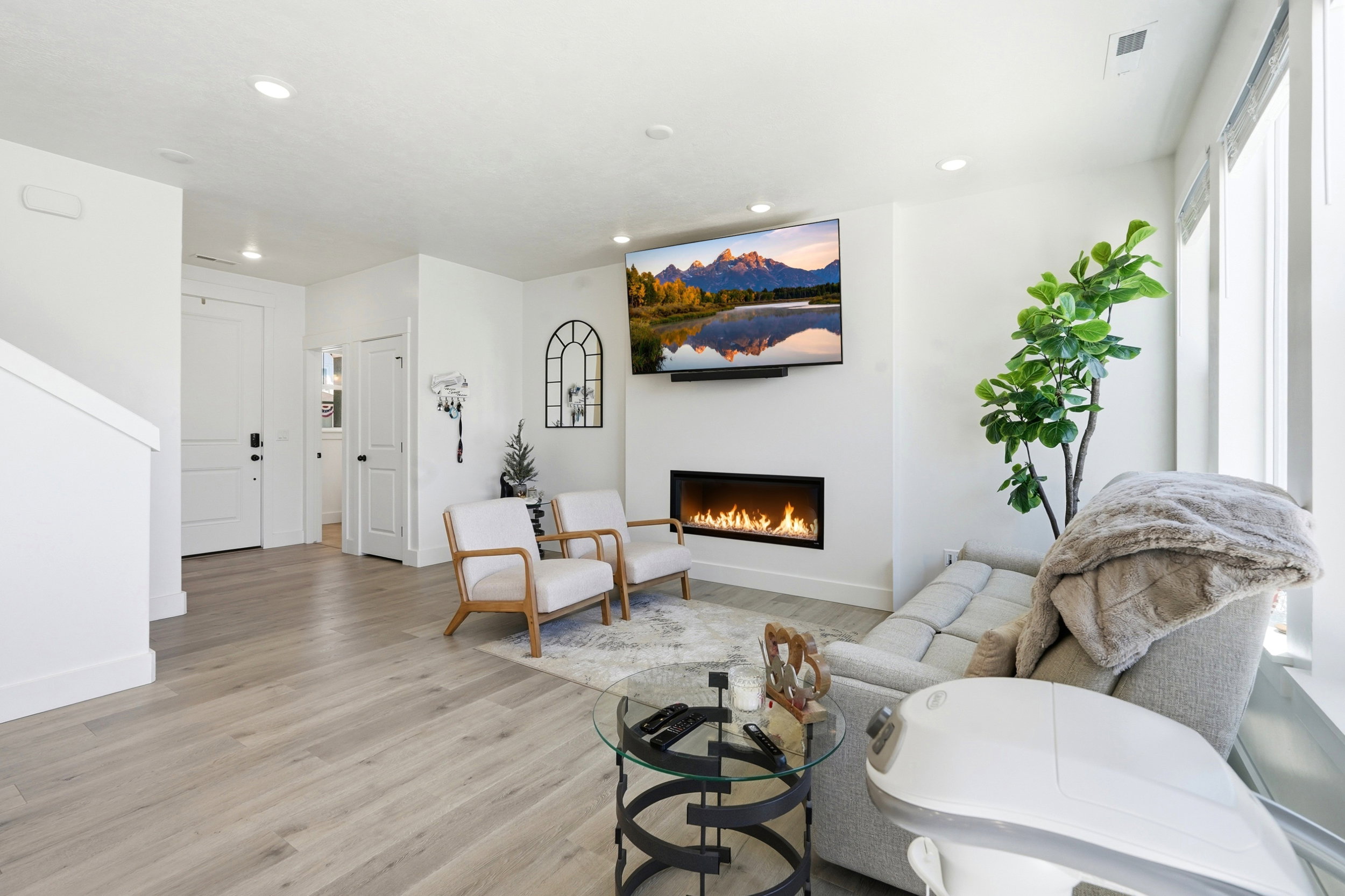 Open living space featuring wood-finish flooring, a linear electric fireplace, and recessed lighting