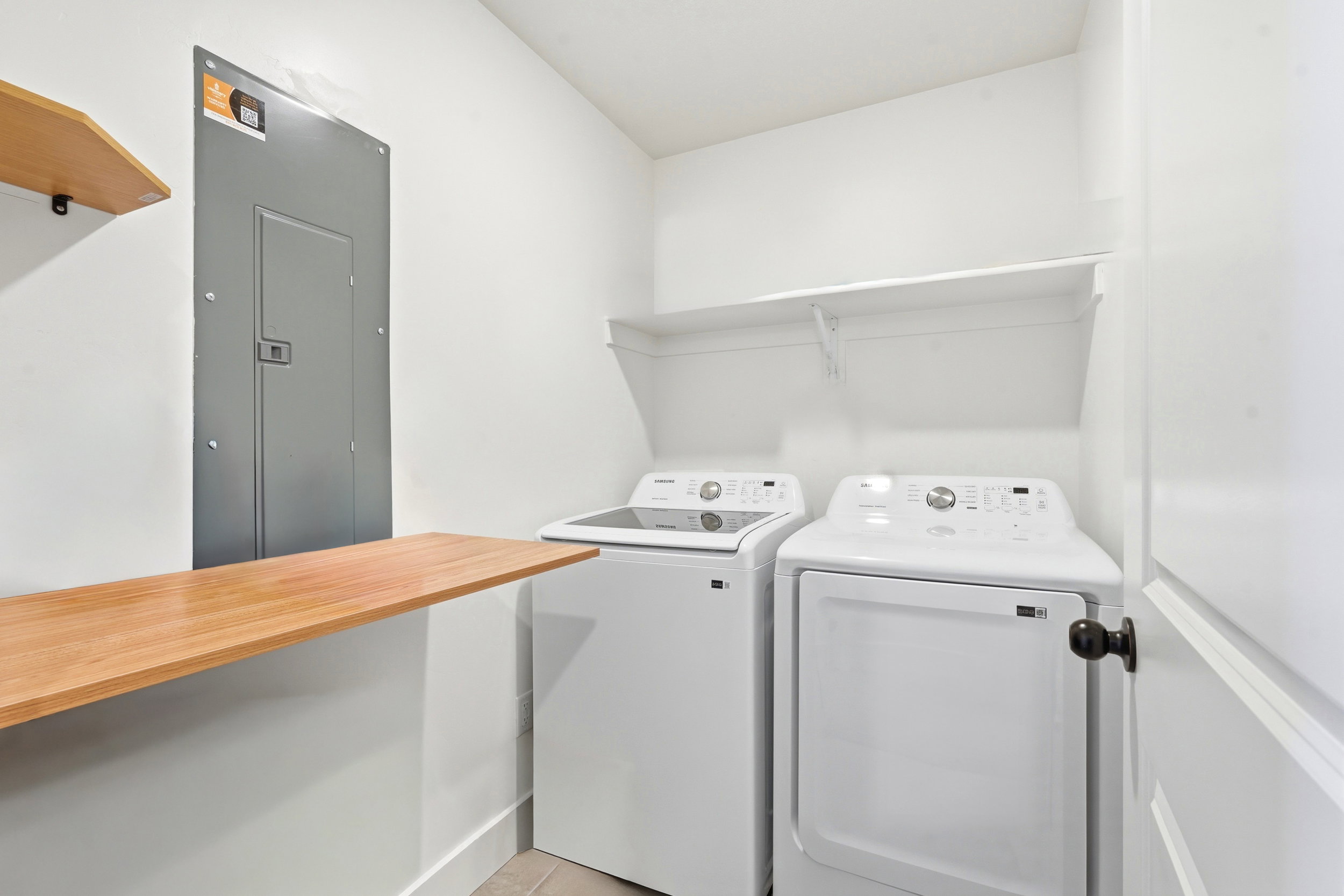 Dedicated utility space featuring a built-in wood-finish folding counter, open shelving, and light-toned flooring
