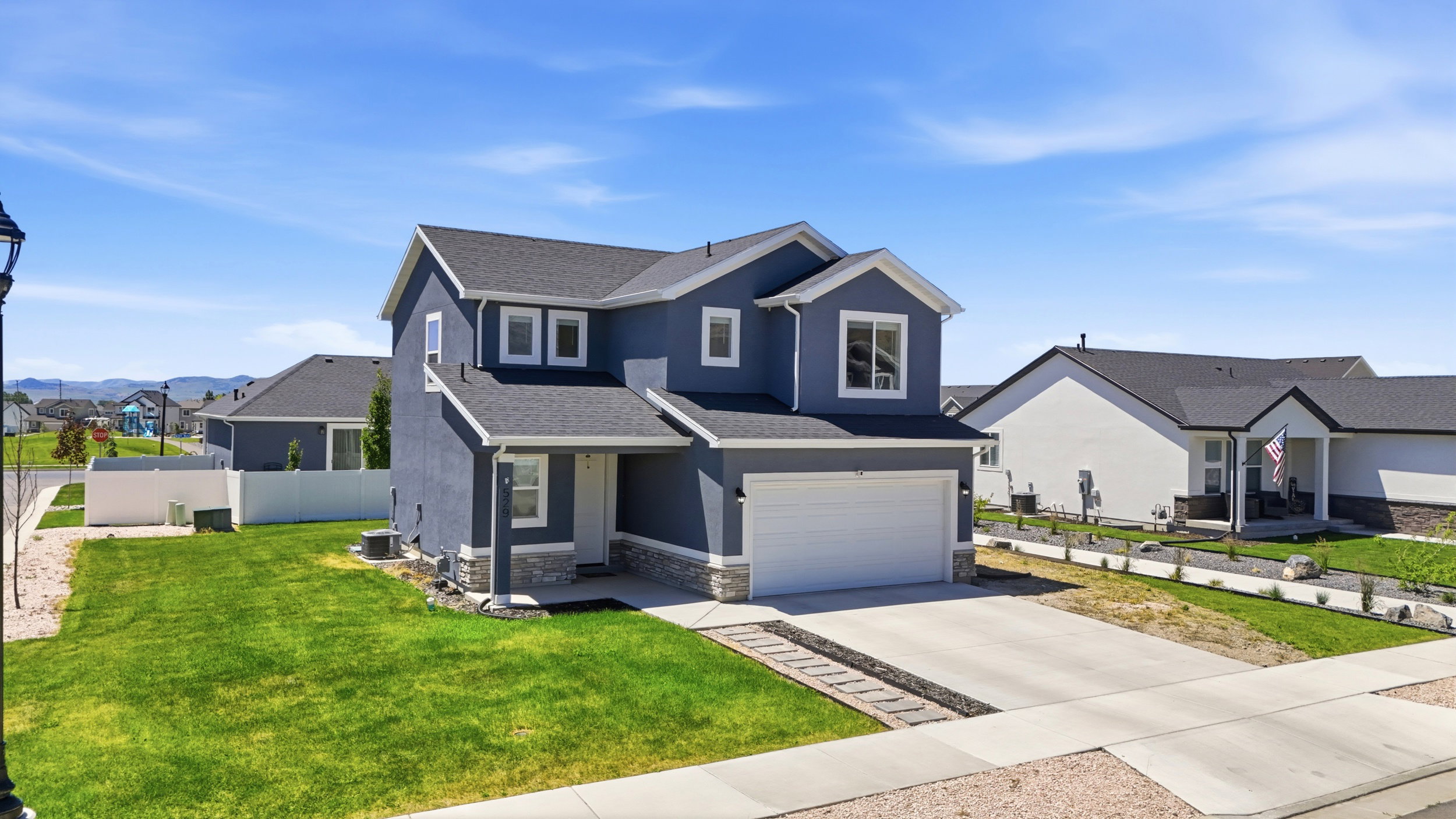 Two-story residence featuring a dark gray exterior with white trim, a two-car garage, concrete driveway, and a front lawn