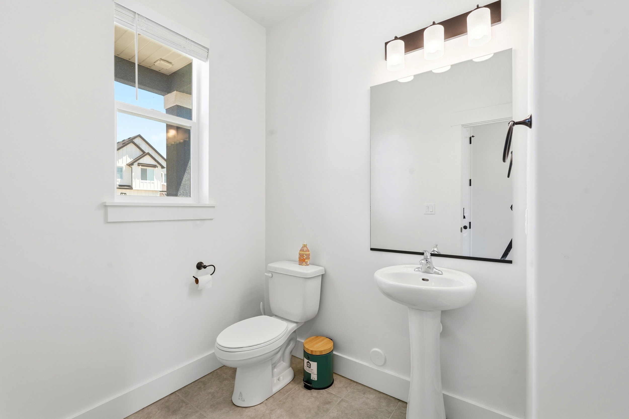 Pedestal sink with chrome faucet, large vanity mirror, and three-light vanity bar