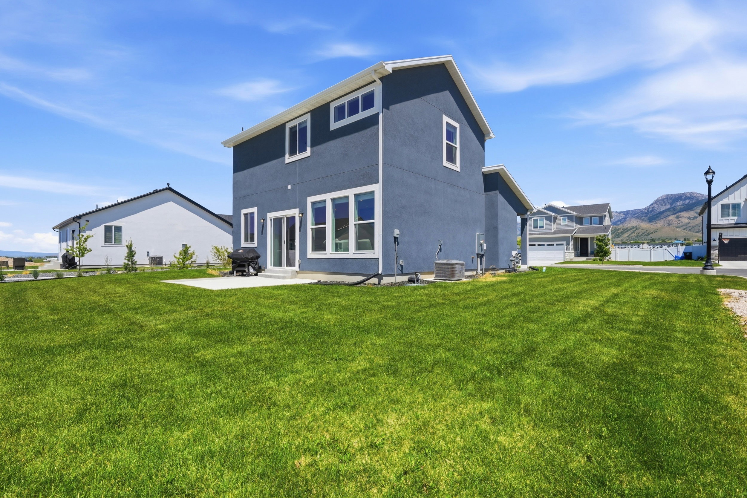 Expansive rear lawn with a concrete patio