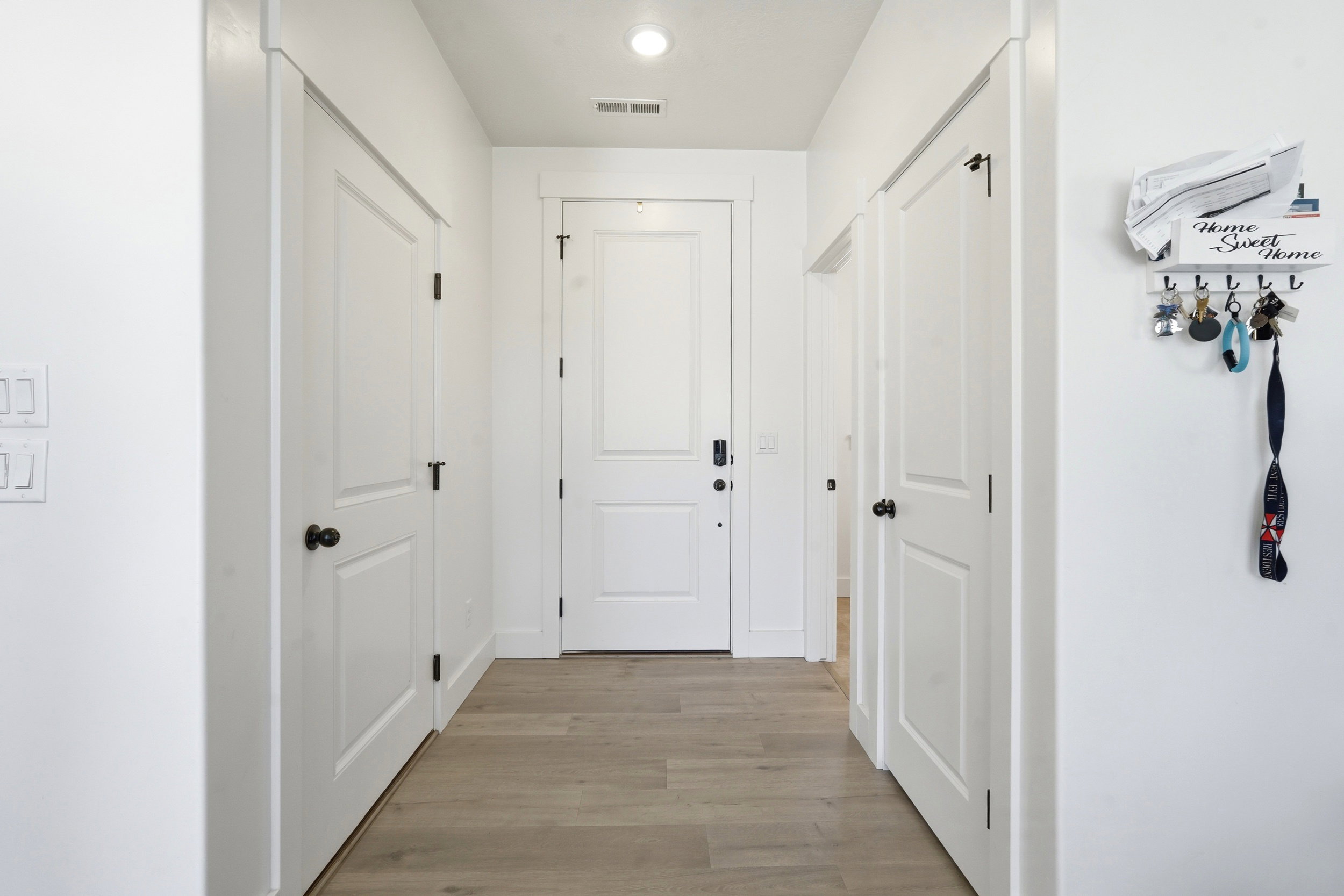 Entryway featuring light wood-finish flooring, white paneled doors, black hardware, and recessed lighting