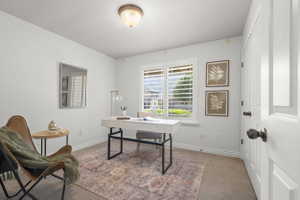 Bright room with a window featuring white plantation shutters, neutral wall paint, and beige carpeting
