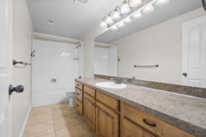 Bathroom featuring a wood-finish vanity with a single basin sink and stone-look countertop