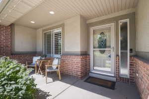 Covered porch entry featuring brick and stucco siding
