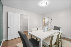 Dining area featuring wood-finish flooring, light neutral wall paint, and a textured green accent wall